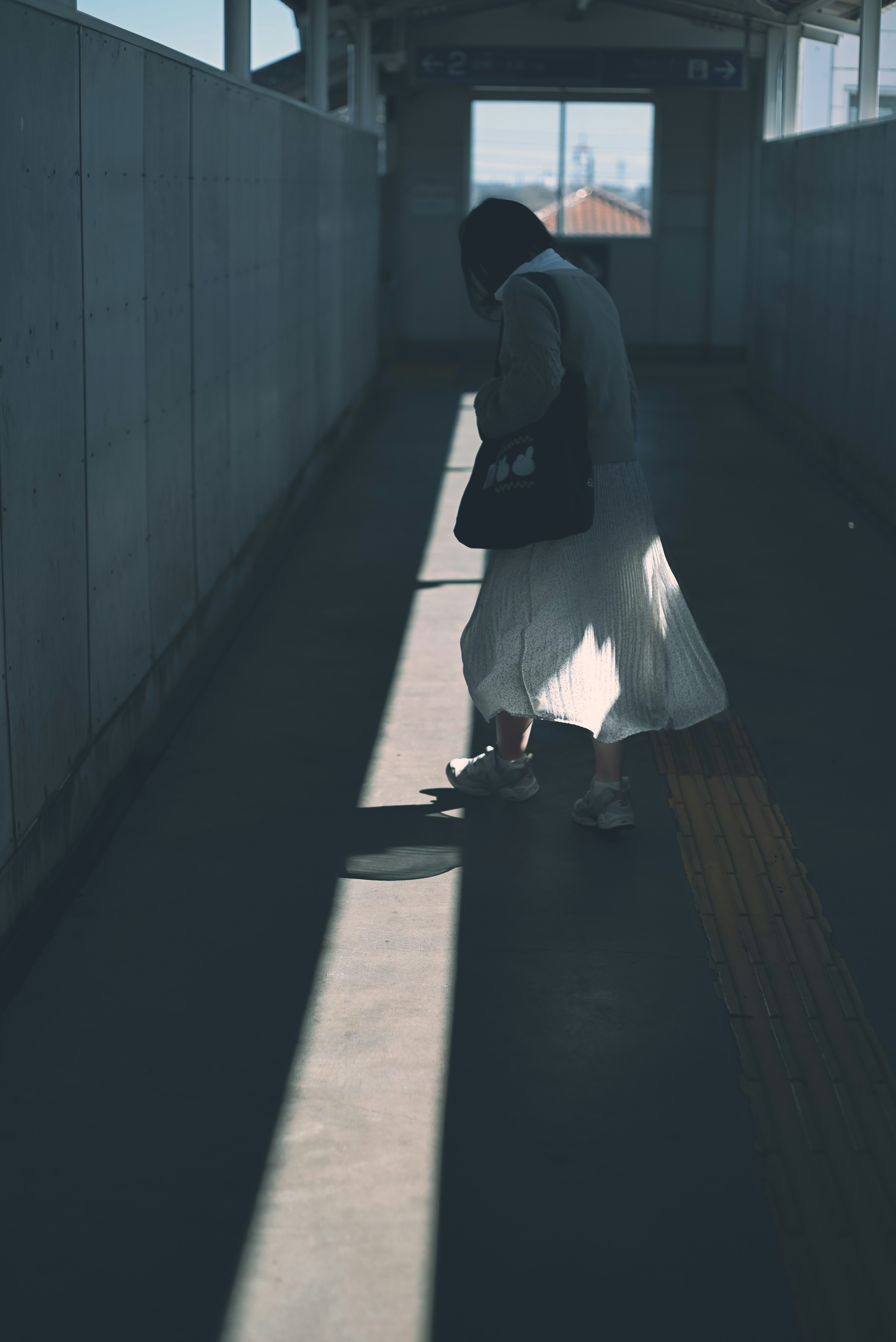 Silhouette of a woman walking in a dim corridor with shadows