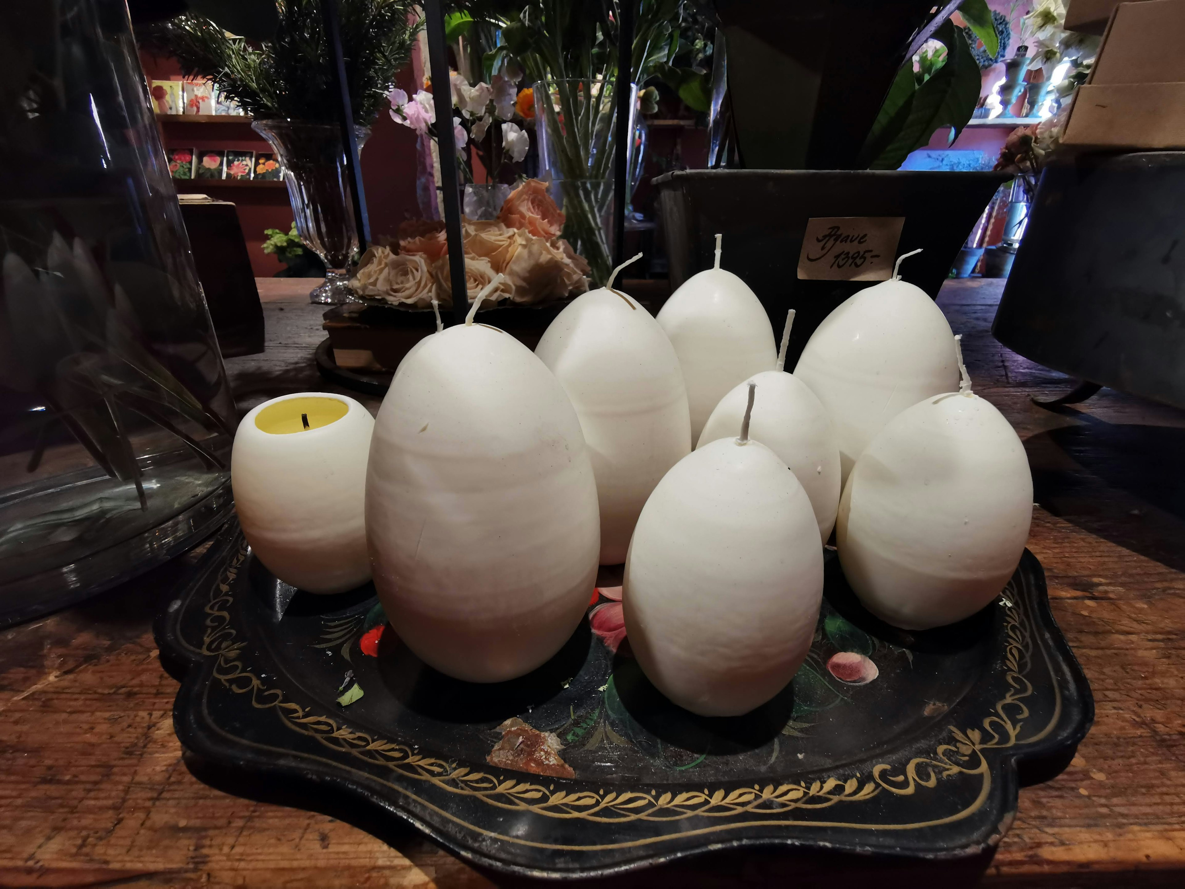 Arrangement of white egg-shaped candles on a decorative tray