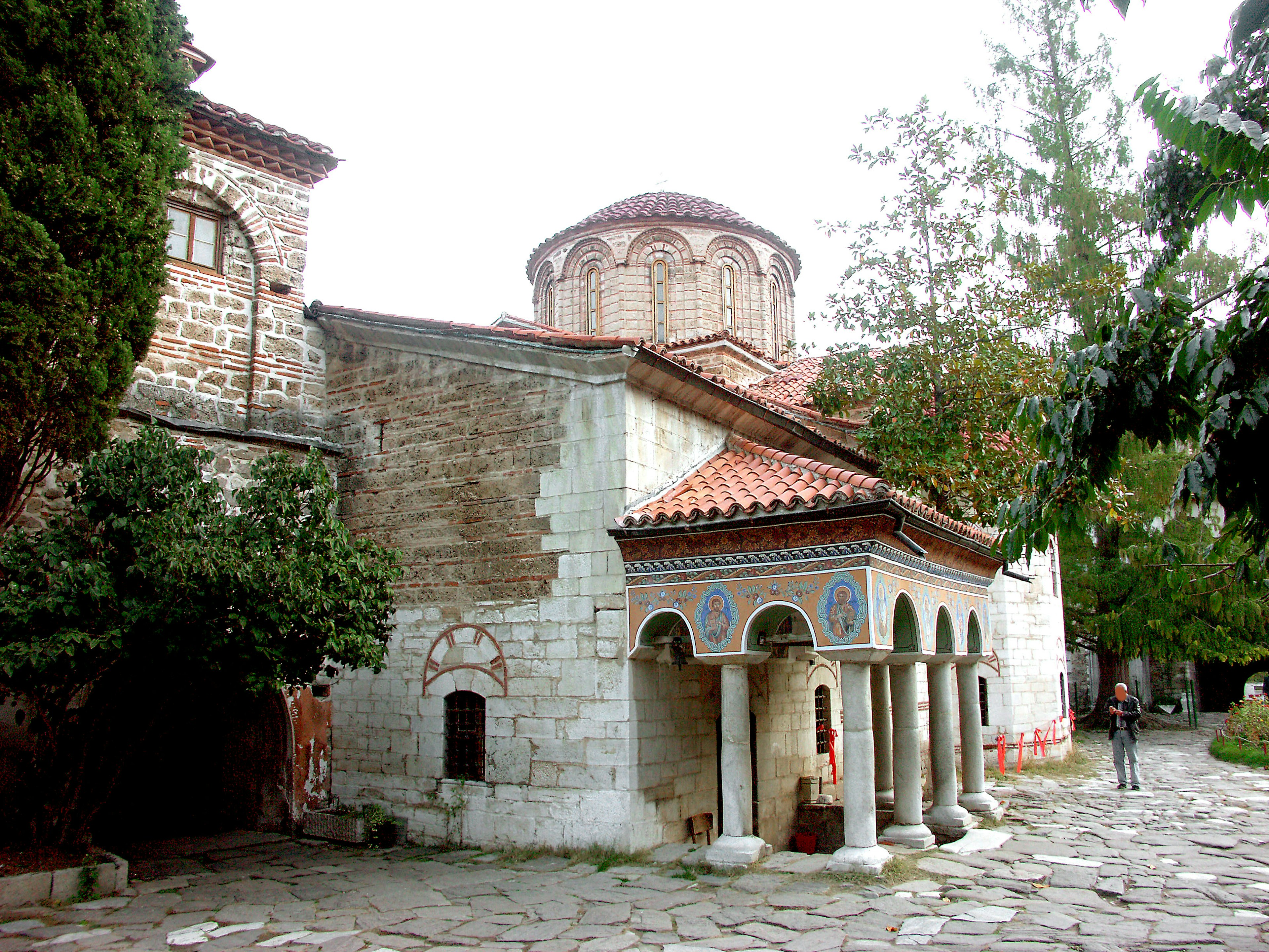 Edificio di chiesa storico con sentiero di pietra circondato da vegetazione e bella arcata