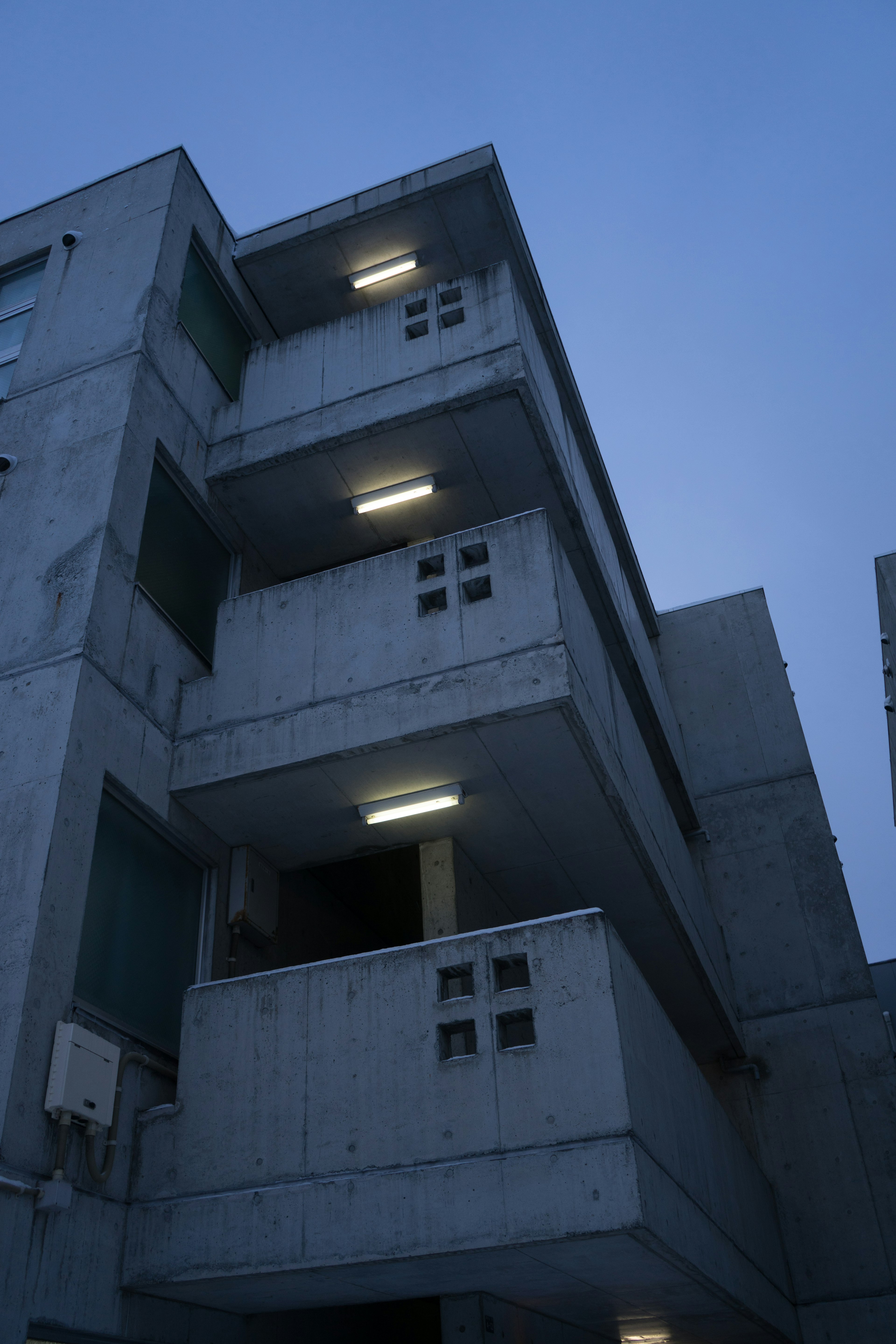 Exterior view of a concrete apartment building under a dim night sky