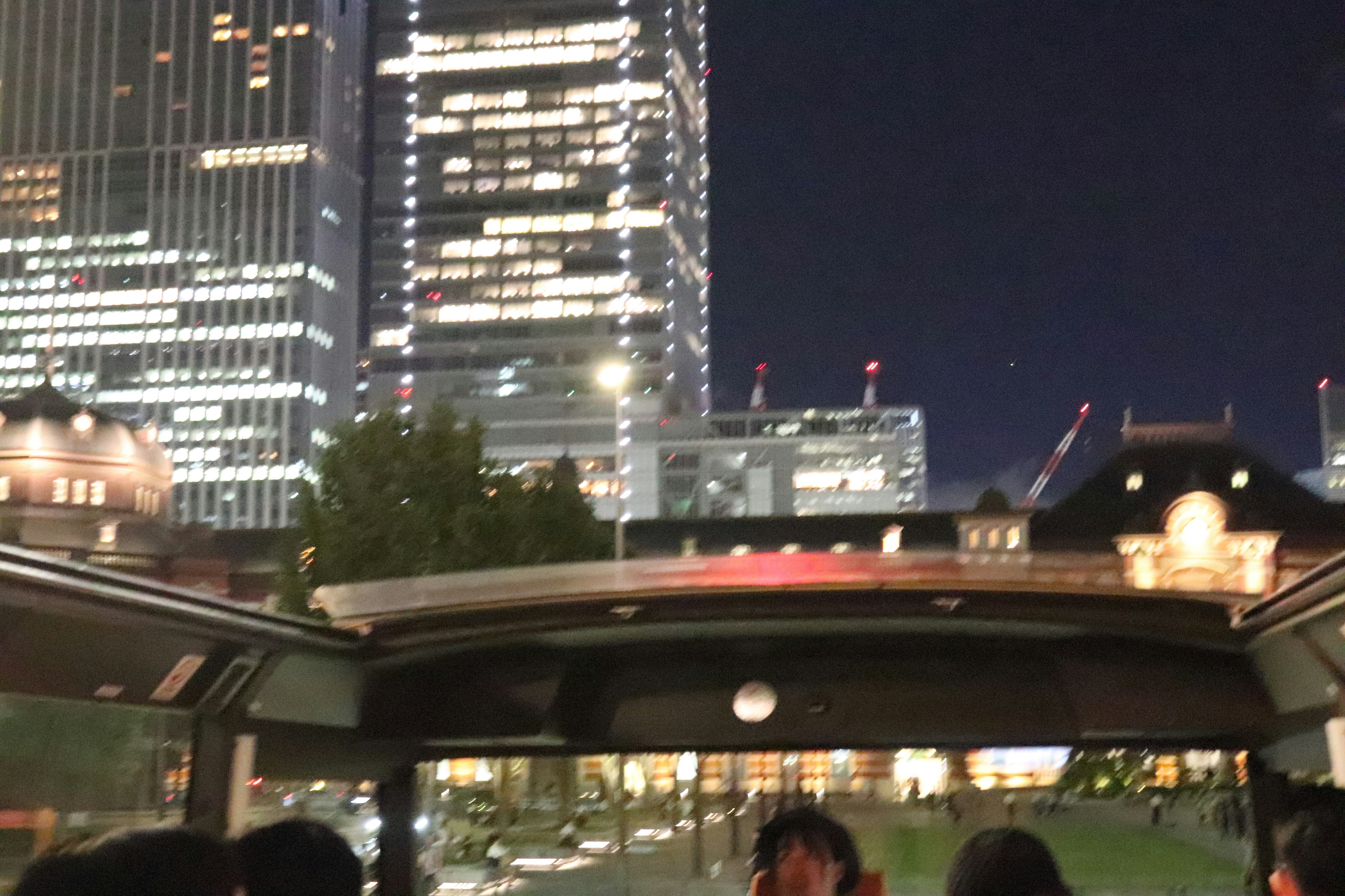 Night view of Tokyo skyscrapers with open-top bus passengers