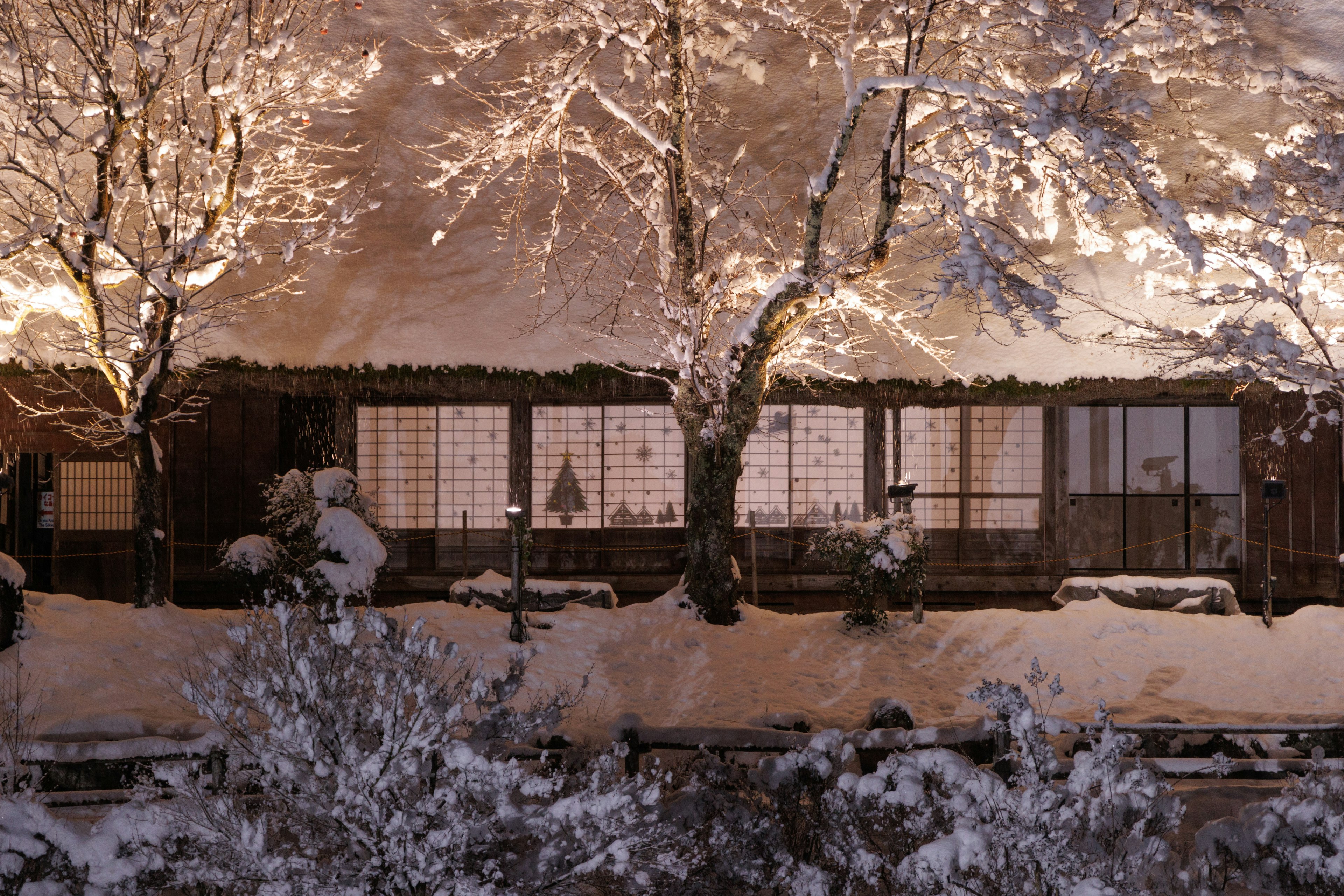 Traditionelles japanisches Haus, das mit Schnee bedeckt ist und warmes Licht hat