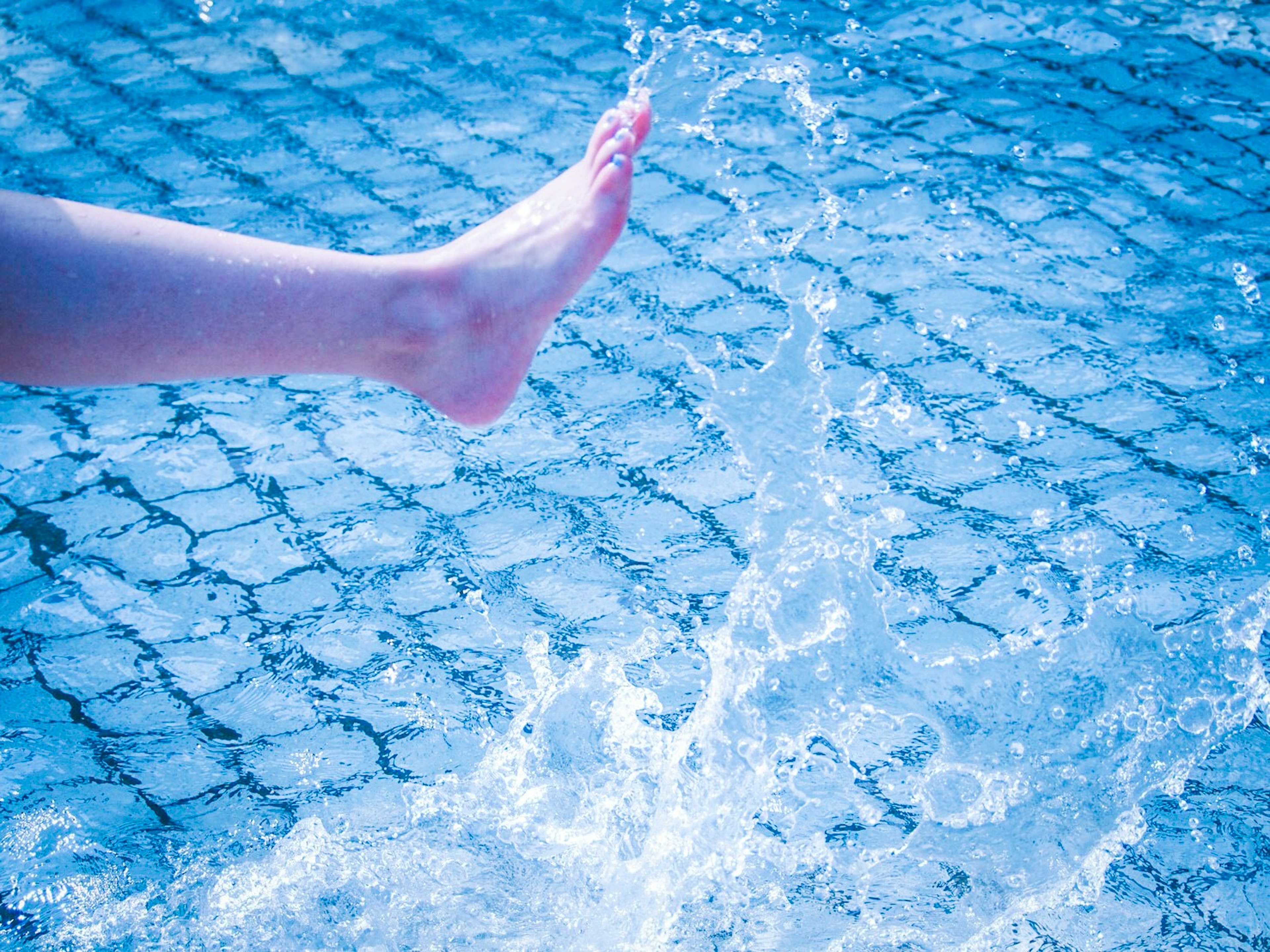 Foot splashing in a puddle on cobblestone