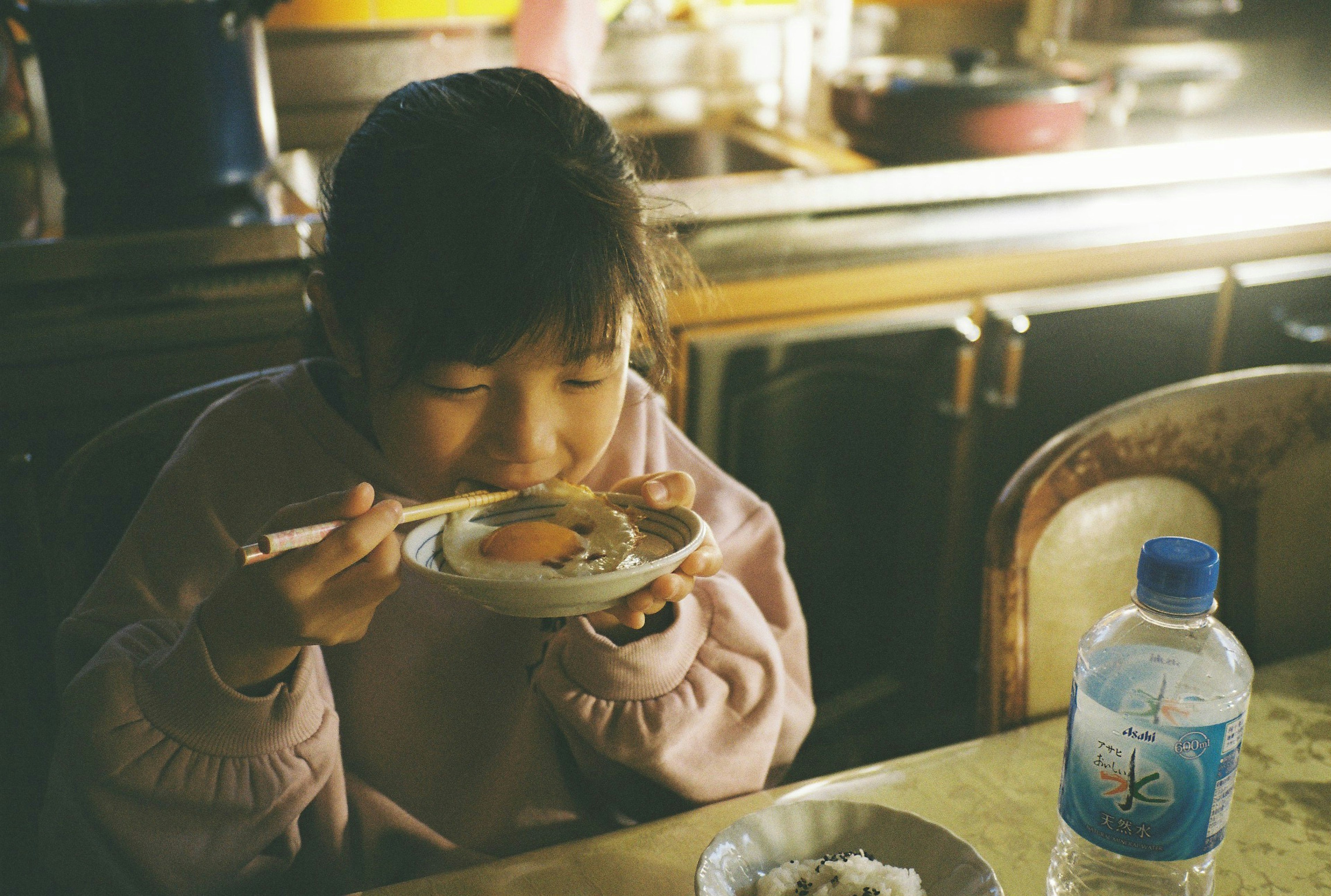 Une fille savourant un repas dans une cuisine chaleureuse