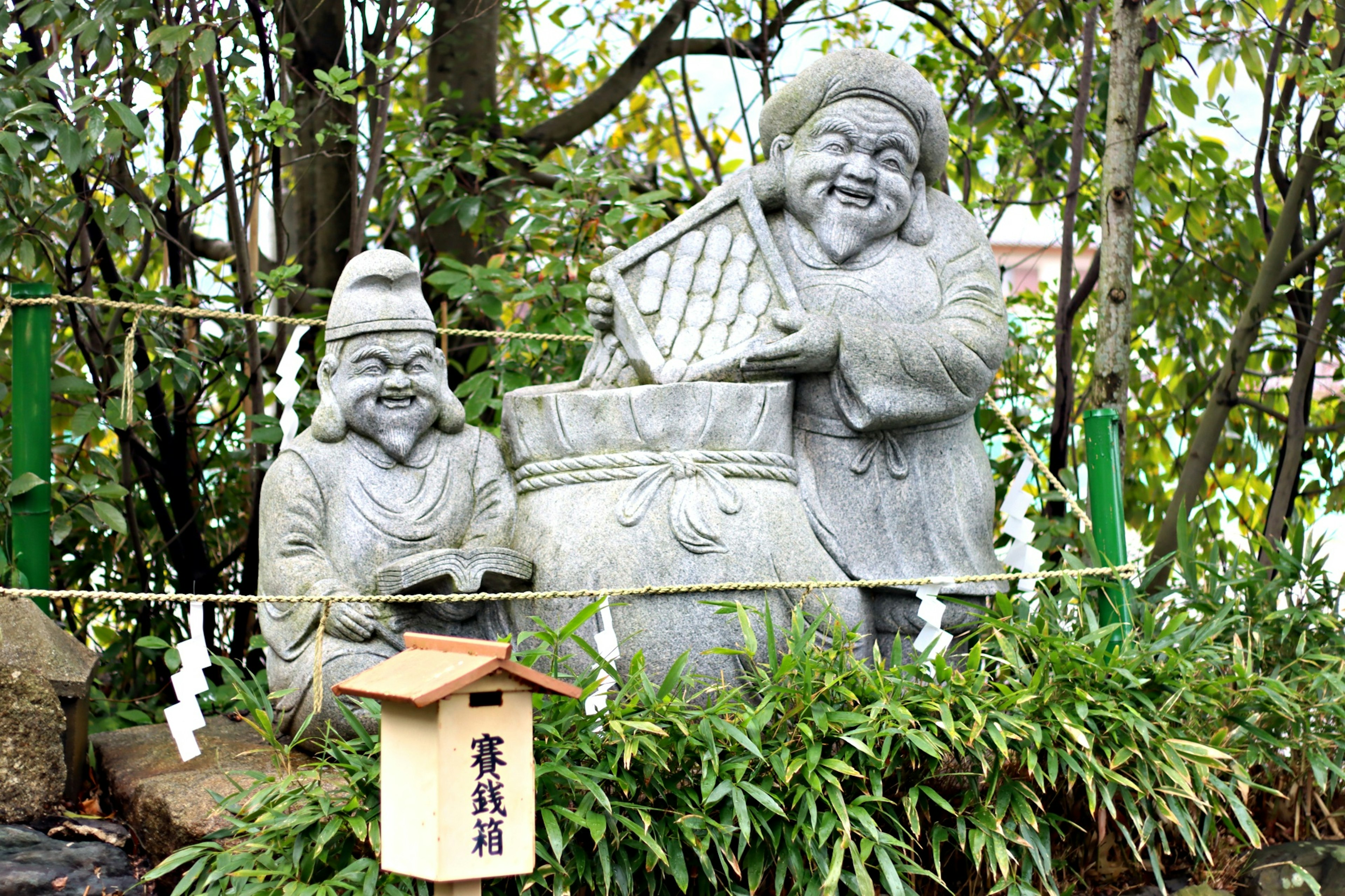 Deux statues de pierre interagissant joyeusement devant un grand pot