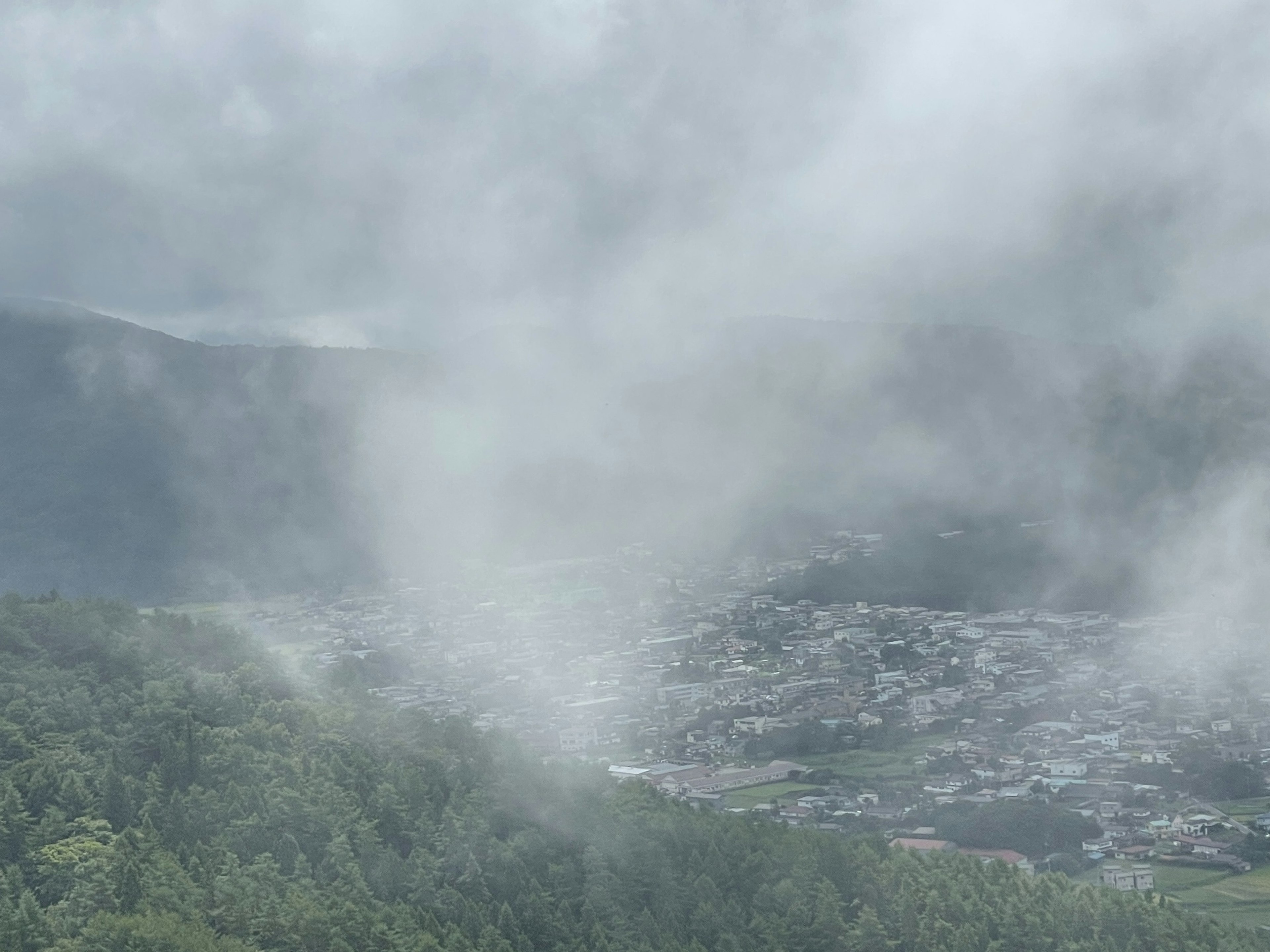 Paisaje nublado con montañas y un pequeño pueblo