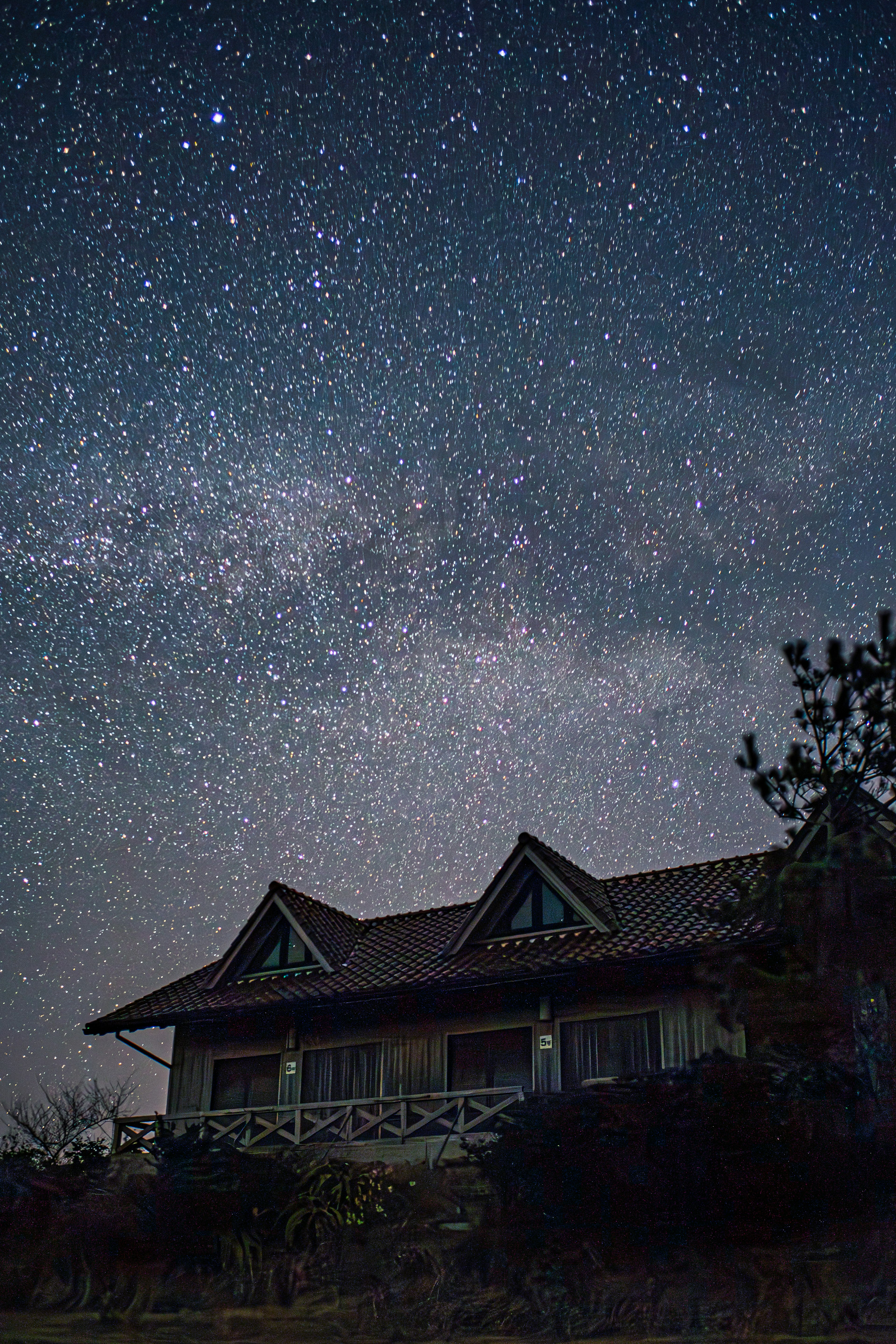 Maison sous un ciel étoilé avec des étoiles et la voie lactée visibles