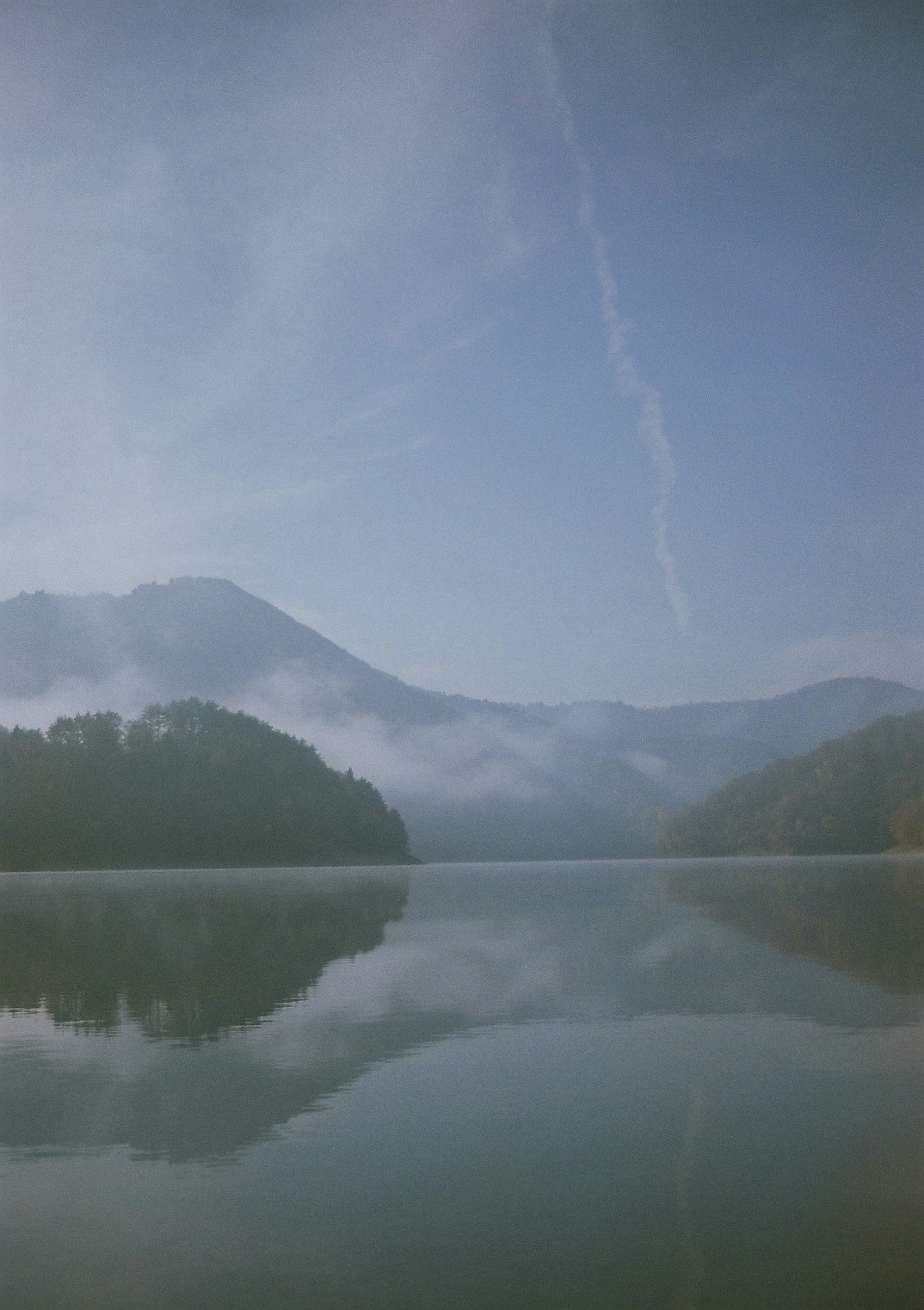 Paisaje sereno de montañas brumosas y lago tranquilo