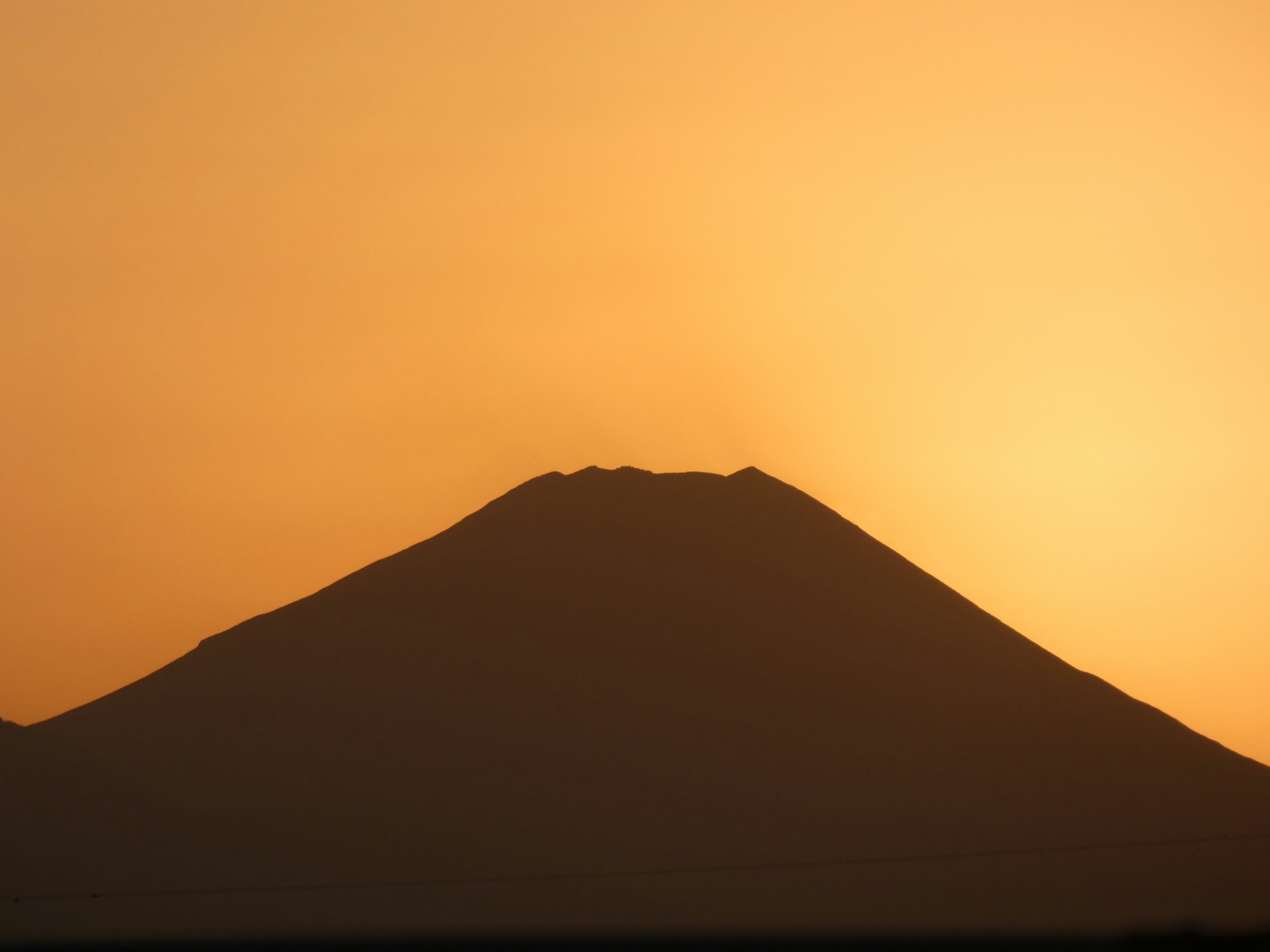 Silhouette of a mountain against a sunset sky