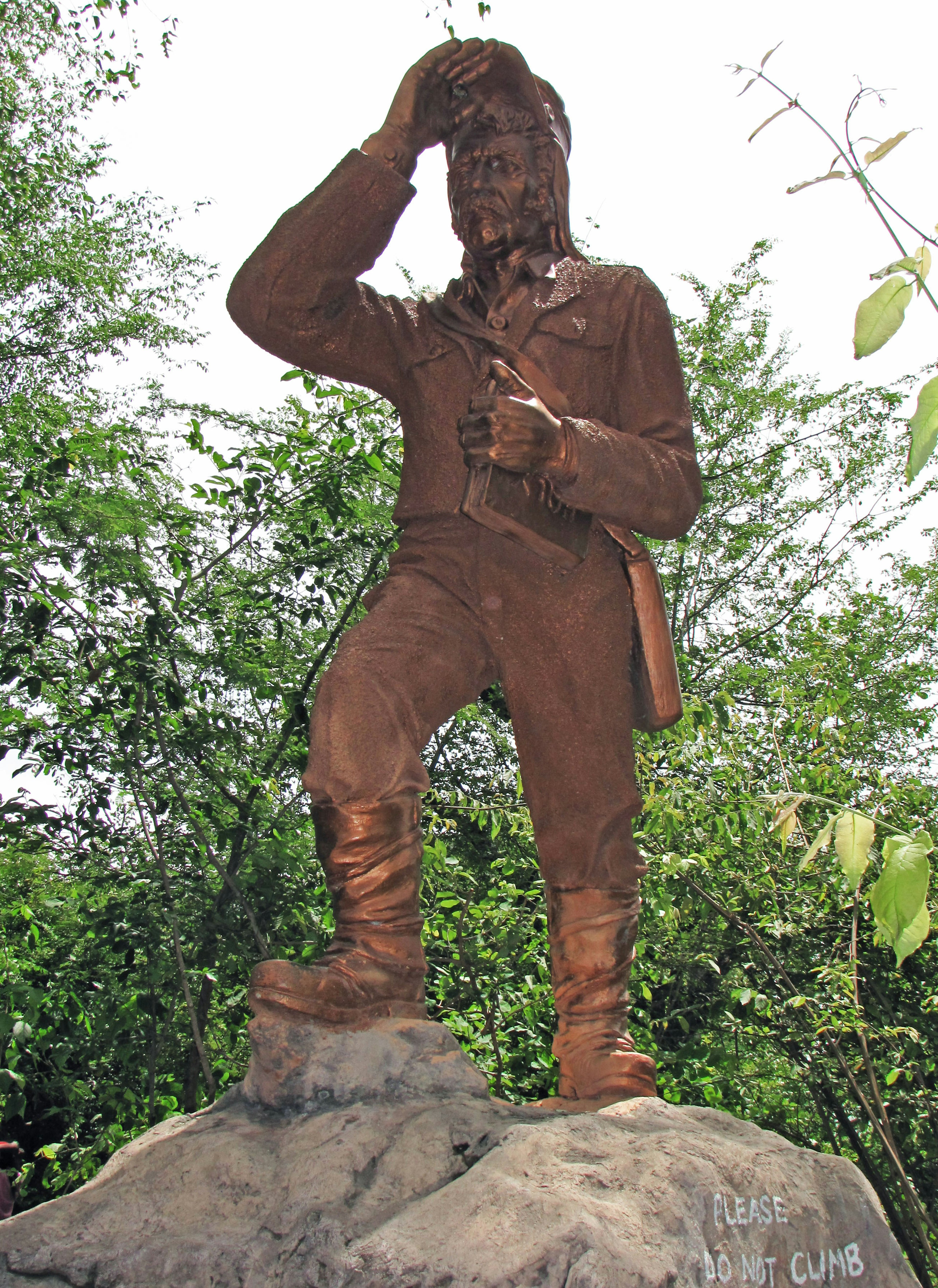 Statua di bronzo di un uomo in piedi con una mano sulla testa