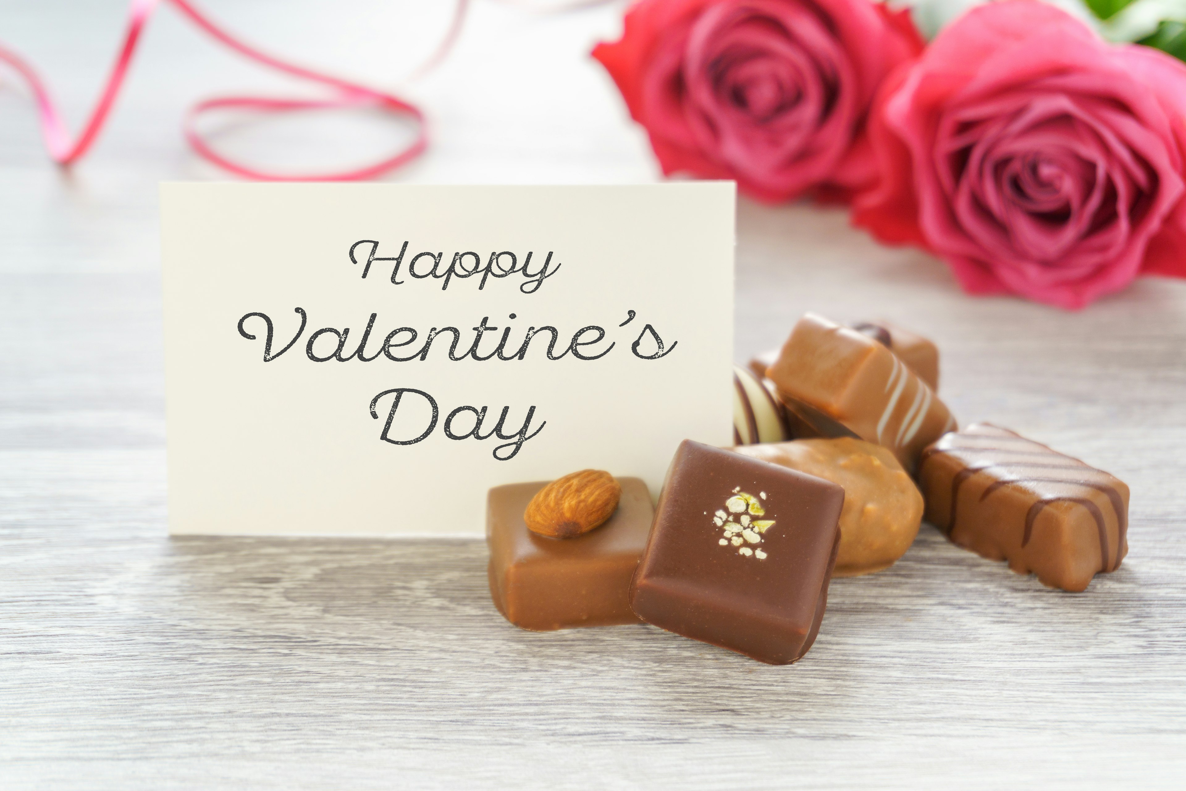 Carte de la Saint-Valentin avec des chocolats assortis et un bouquet de roses rouges