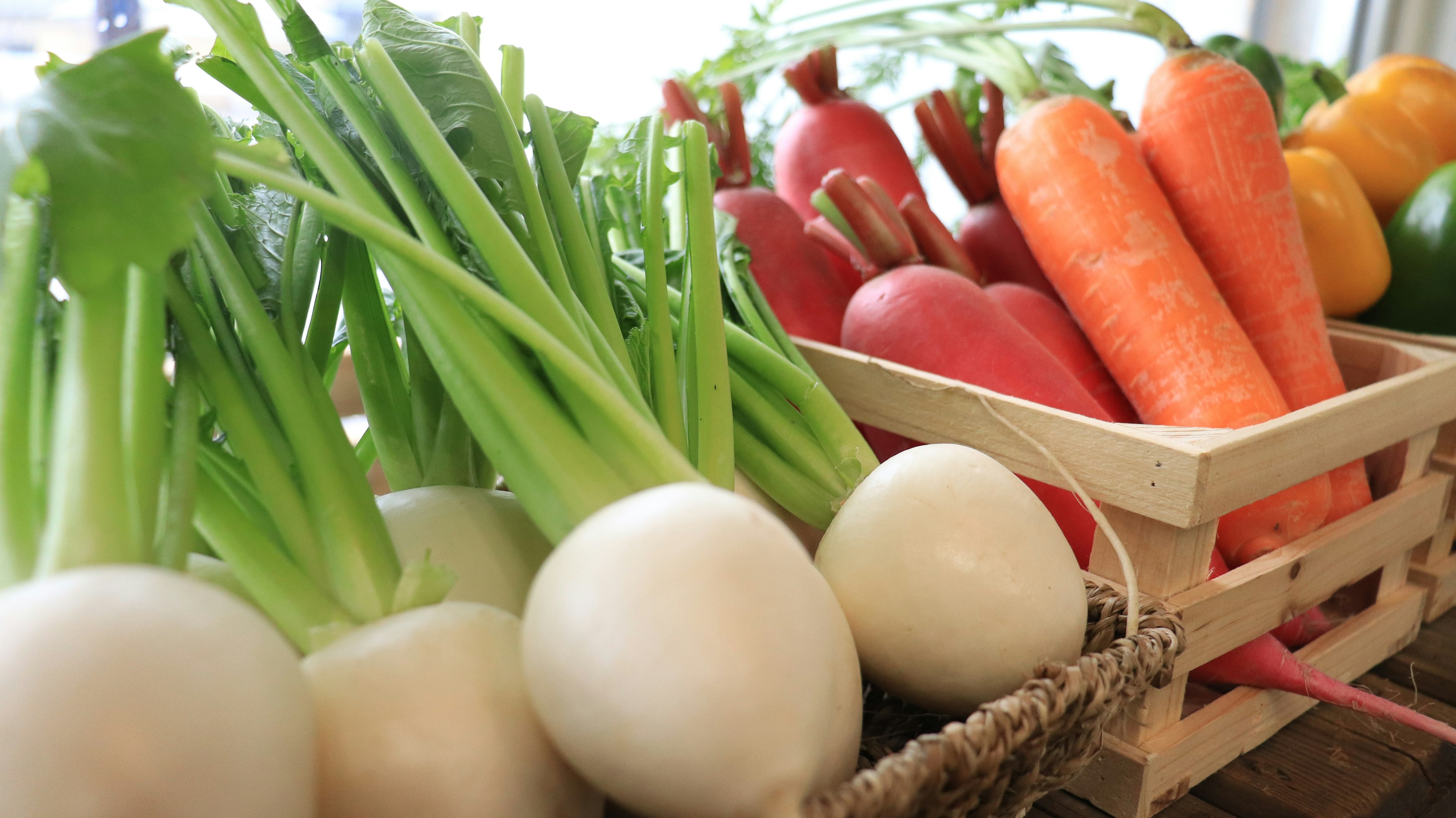 Fresh vegetables displayed at a market including radishes carrots and bell peppers