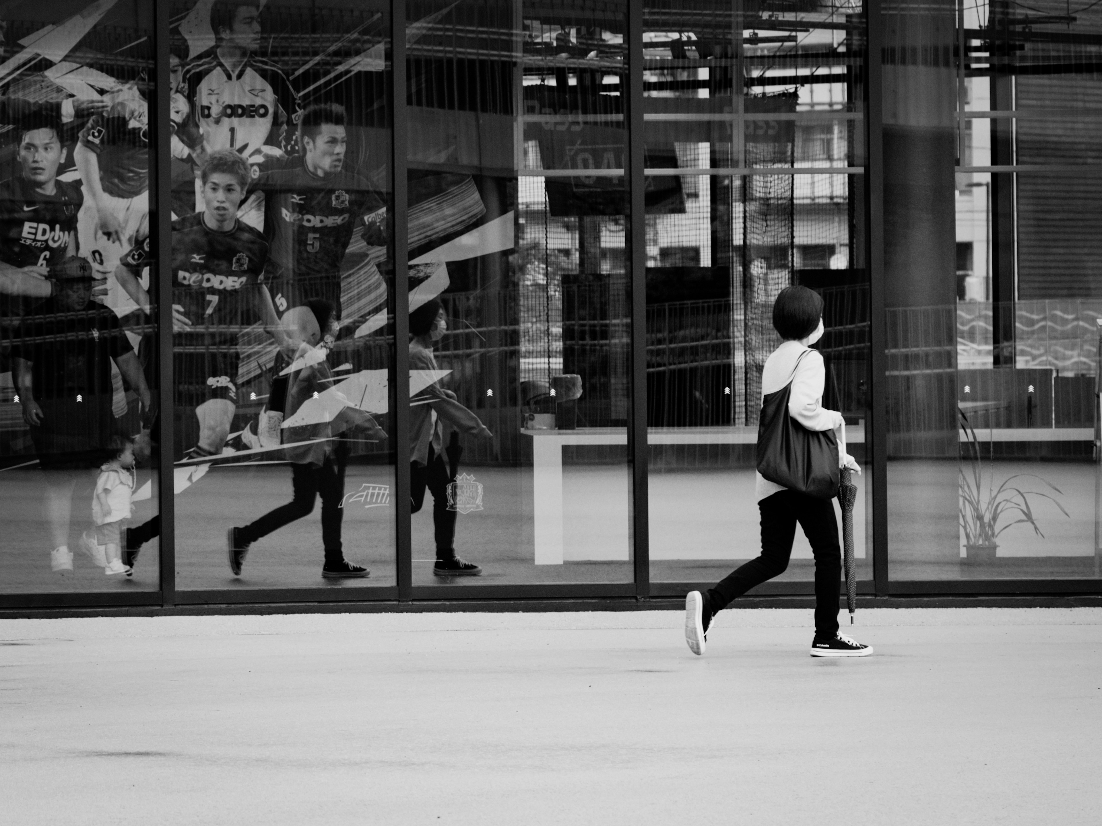 Vue latérale d'une femme marchant en noir et blanc reflets de personnes dans des fenêtres en verre