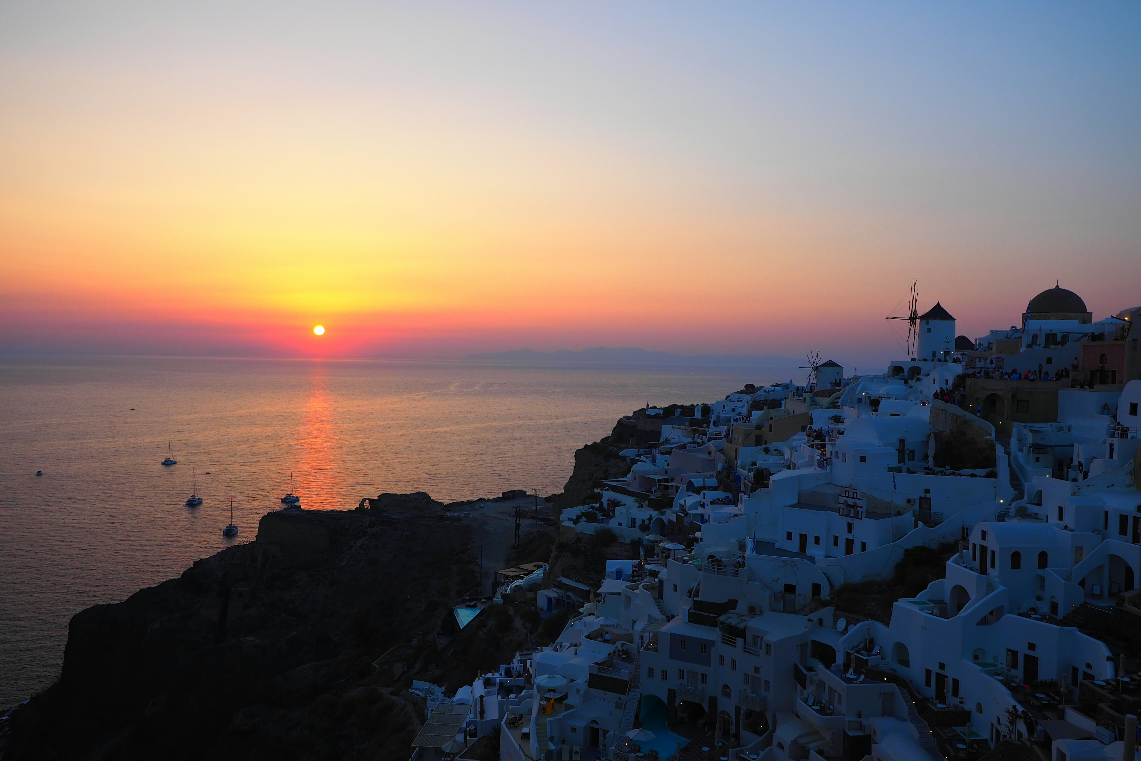 Sonnenuntergangsblick auf Santorin mit weißen Gebäuden und blauem Meer