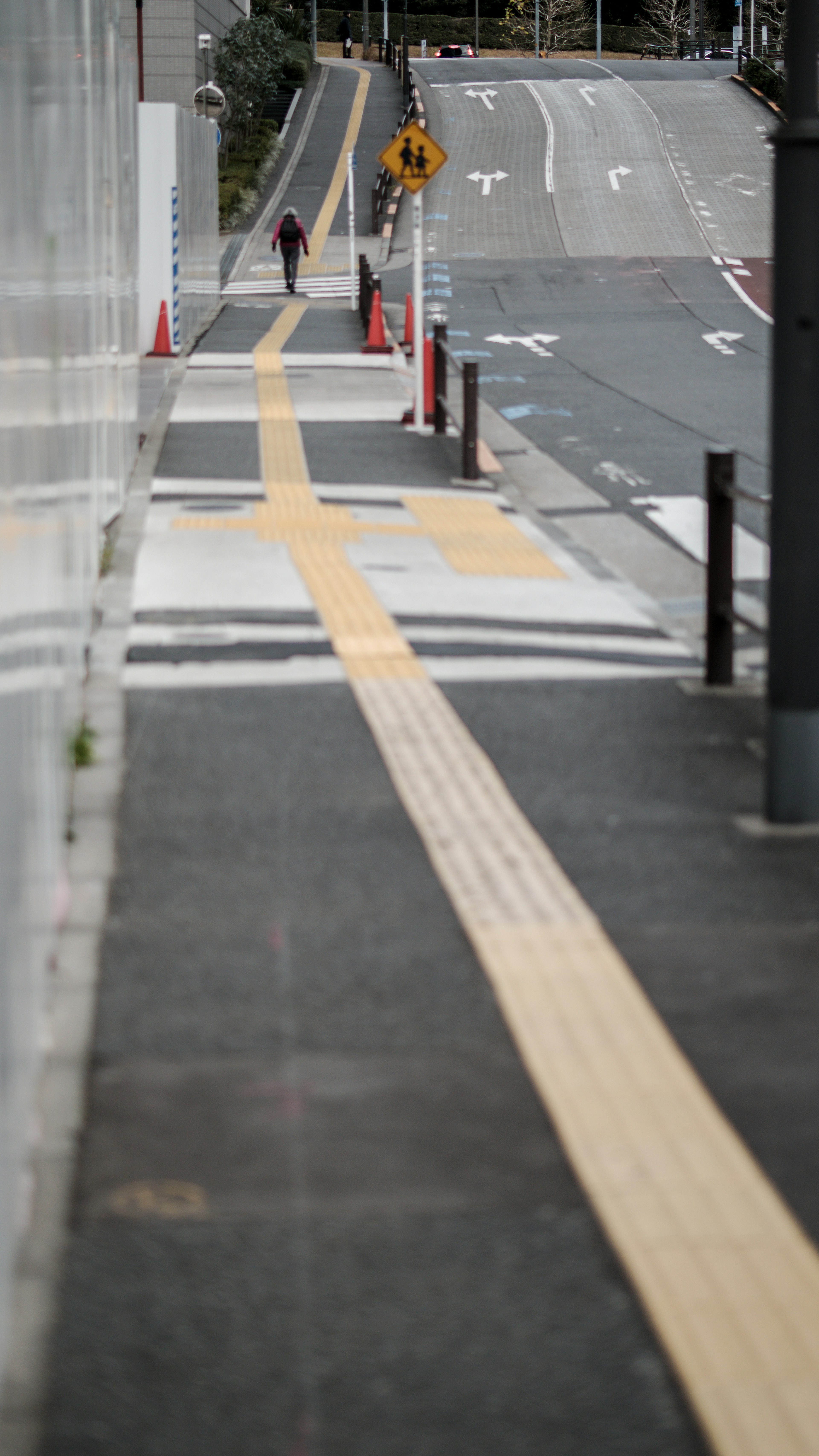 Paved sidewalk with yellow guide line and pedestrian