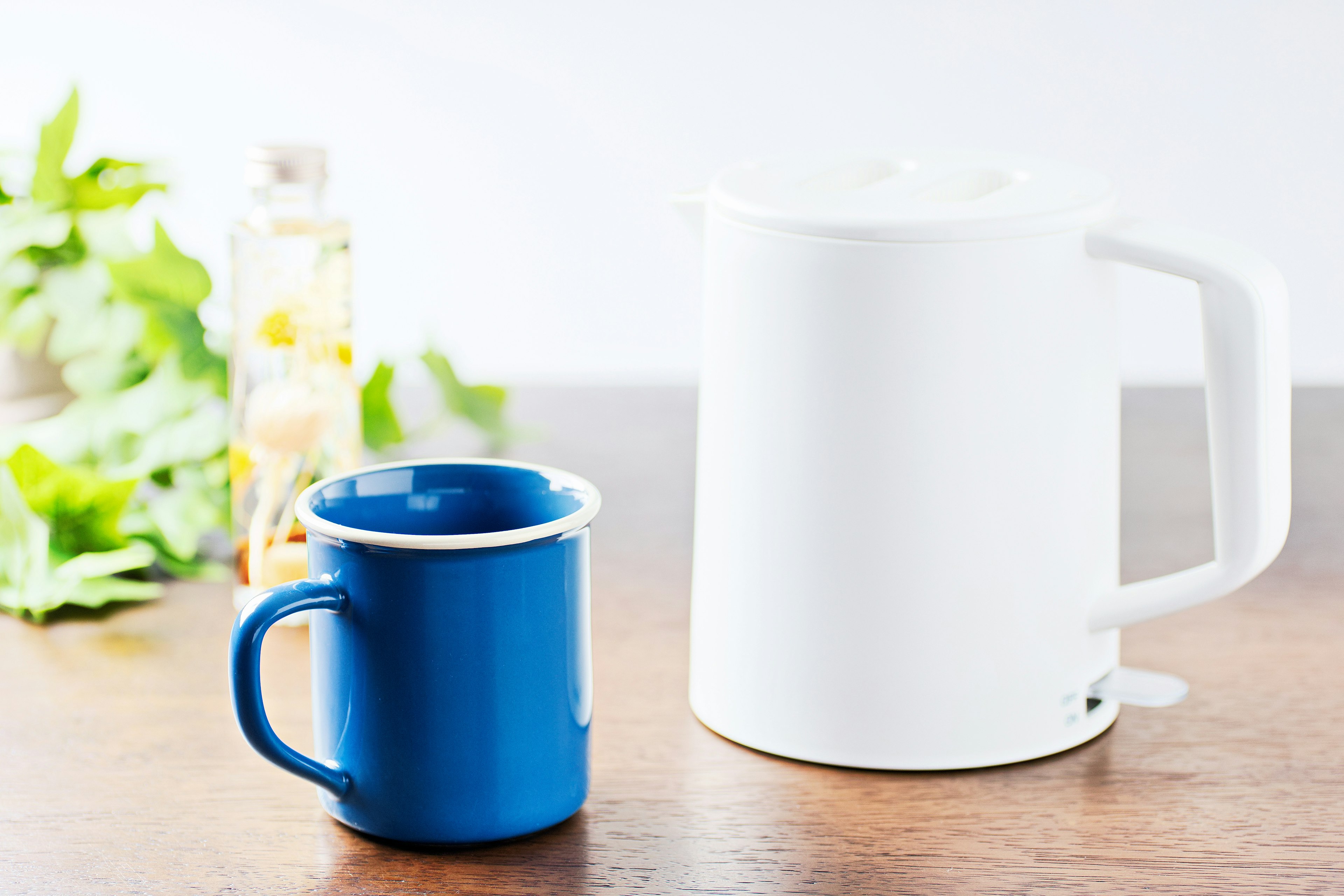 Hervidor eléctrico blanco y taza azul sobre una mesa de madera