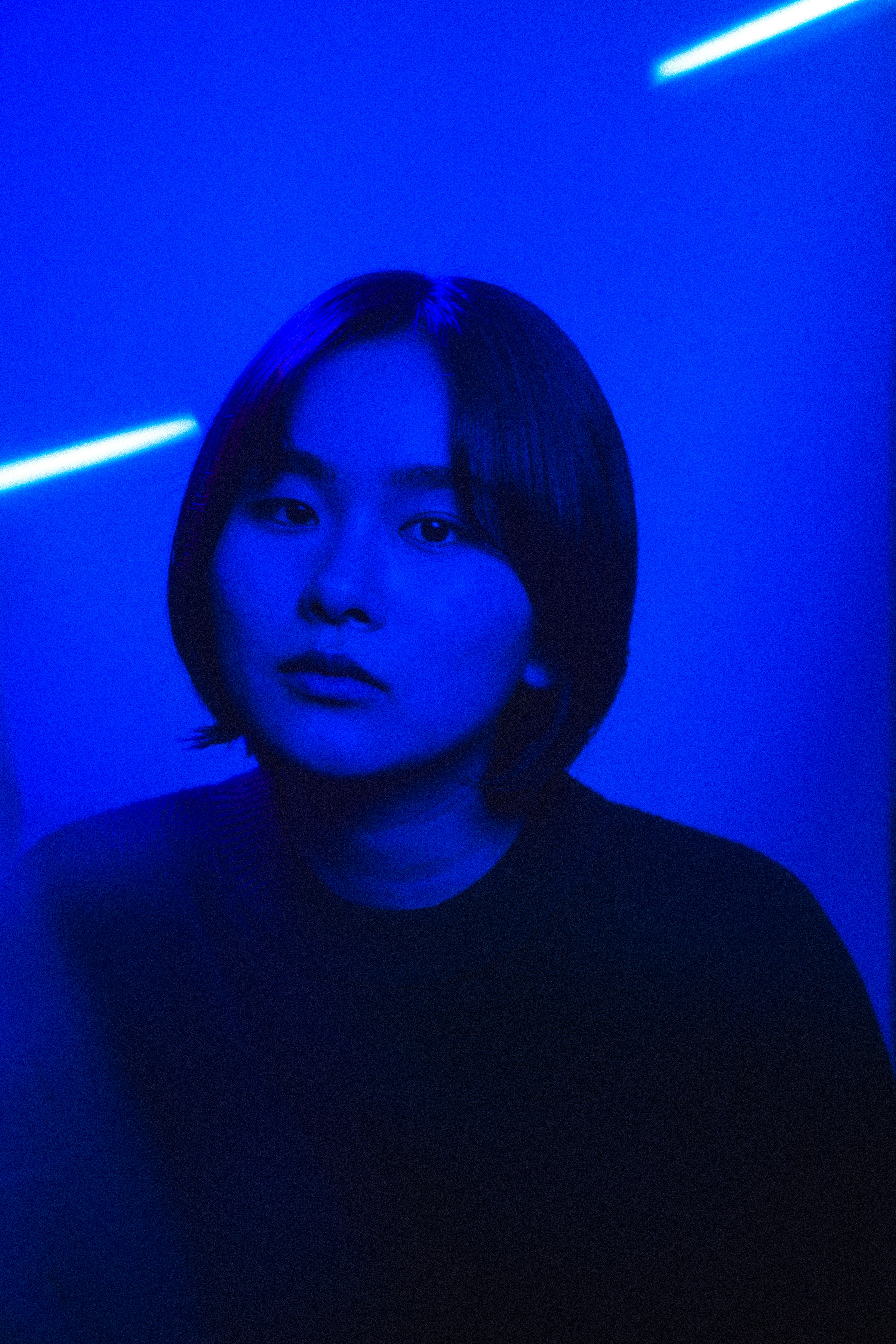 Portrait d'une femme avec une expression sérieuse sous une lumière bleue