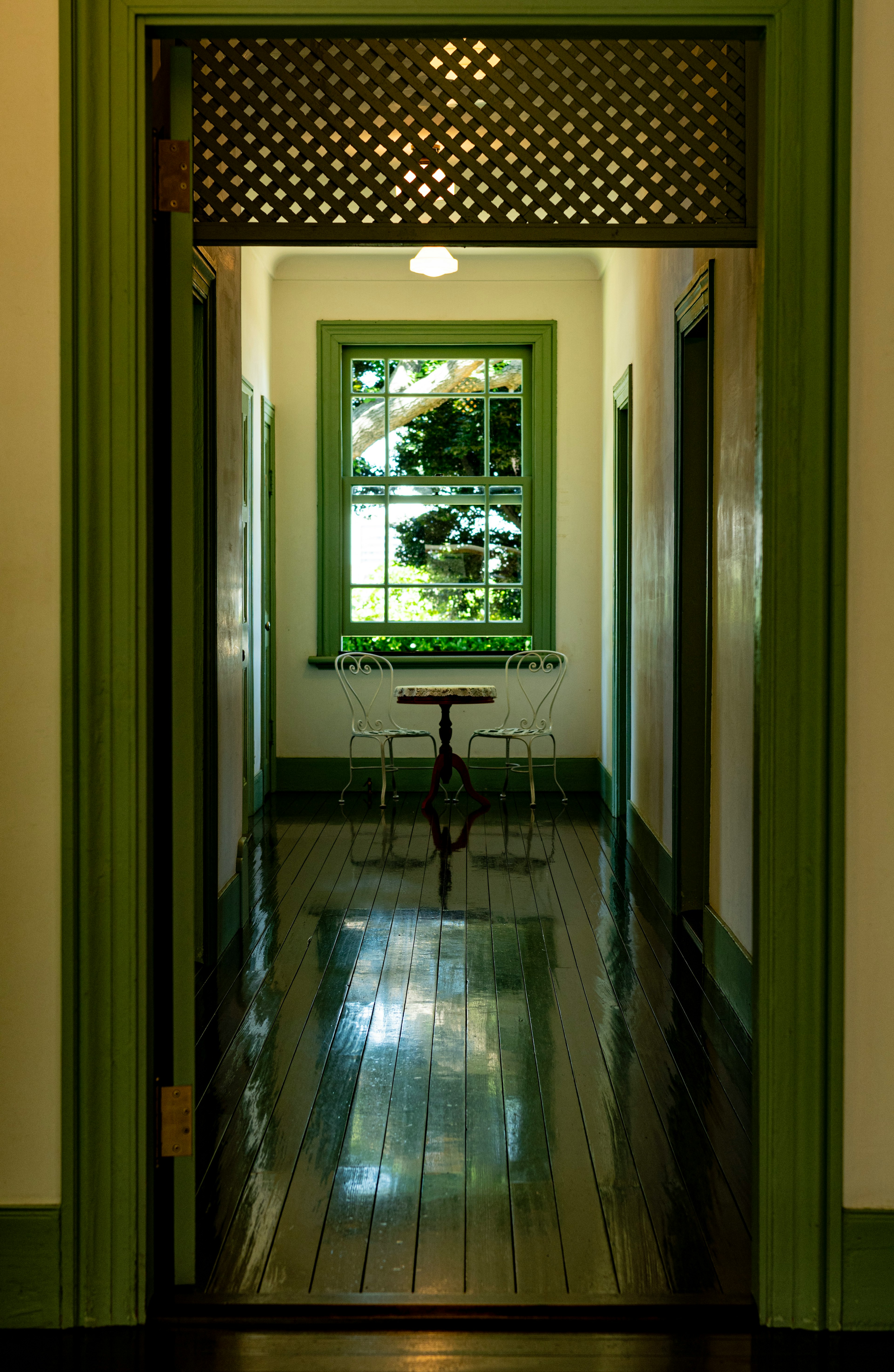 Foto de un pasillo con una ventana de marco verde que presenta una mesa y sillas