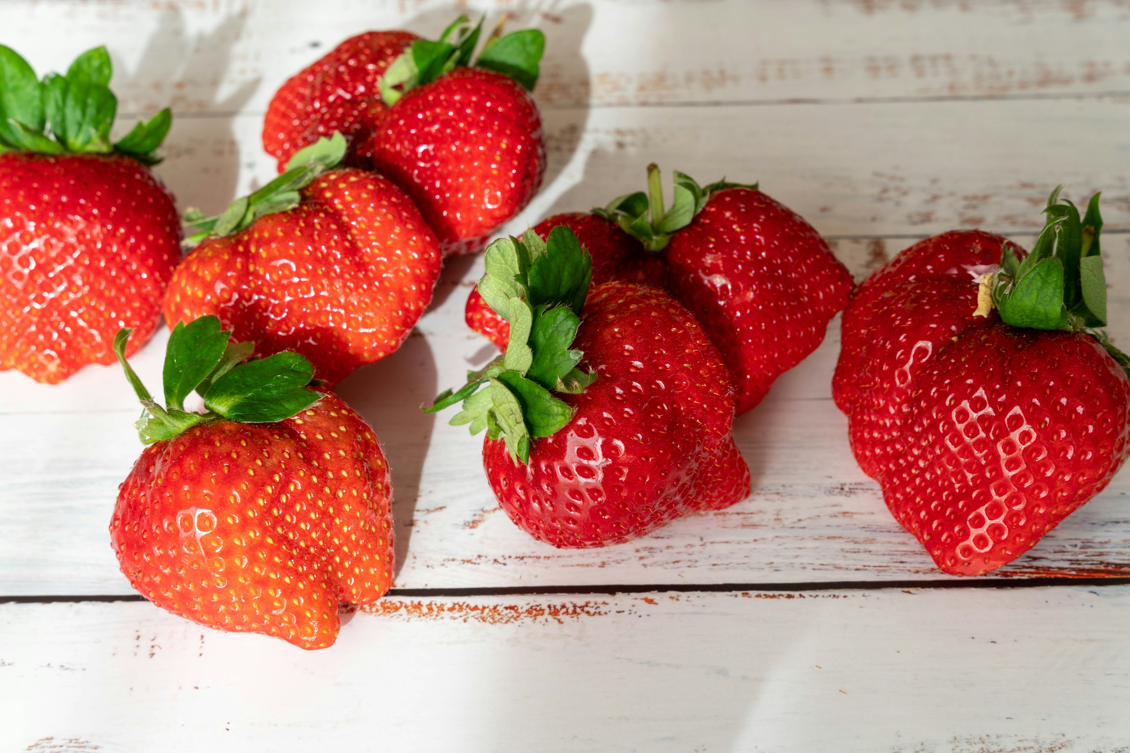 Fraises fraîches disposées sur une table en bois blanc