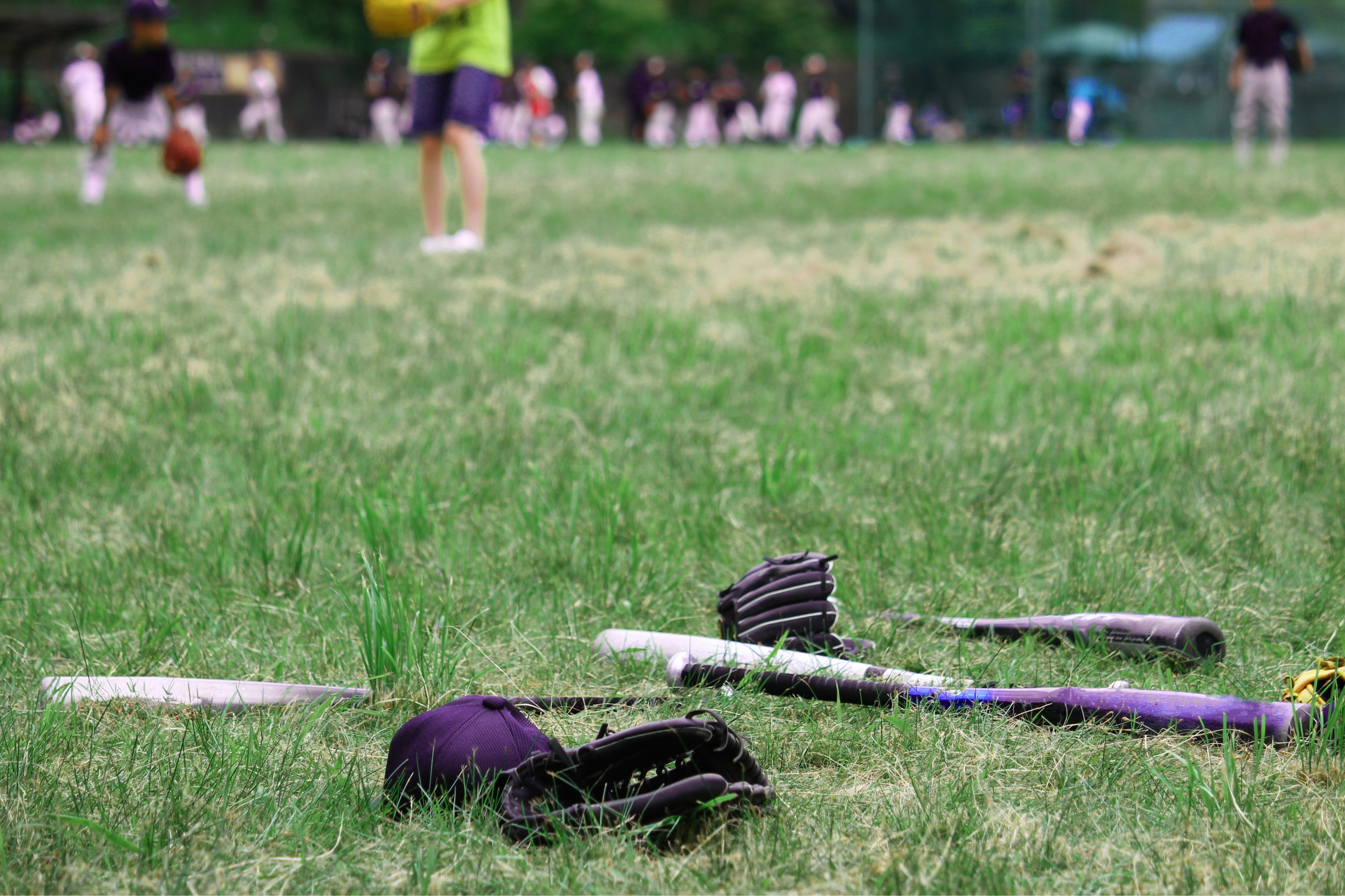 Peralatan baseball di rumput dengan pemain di latar belakang