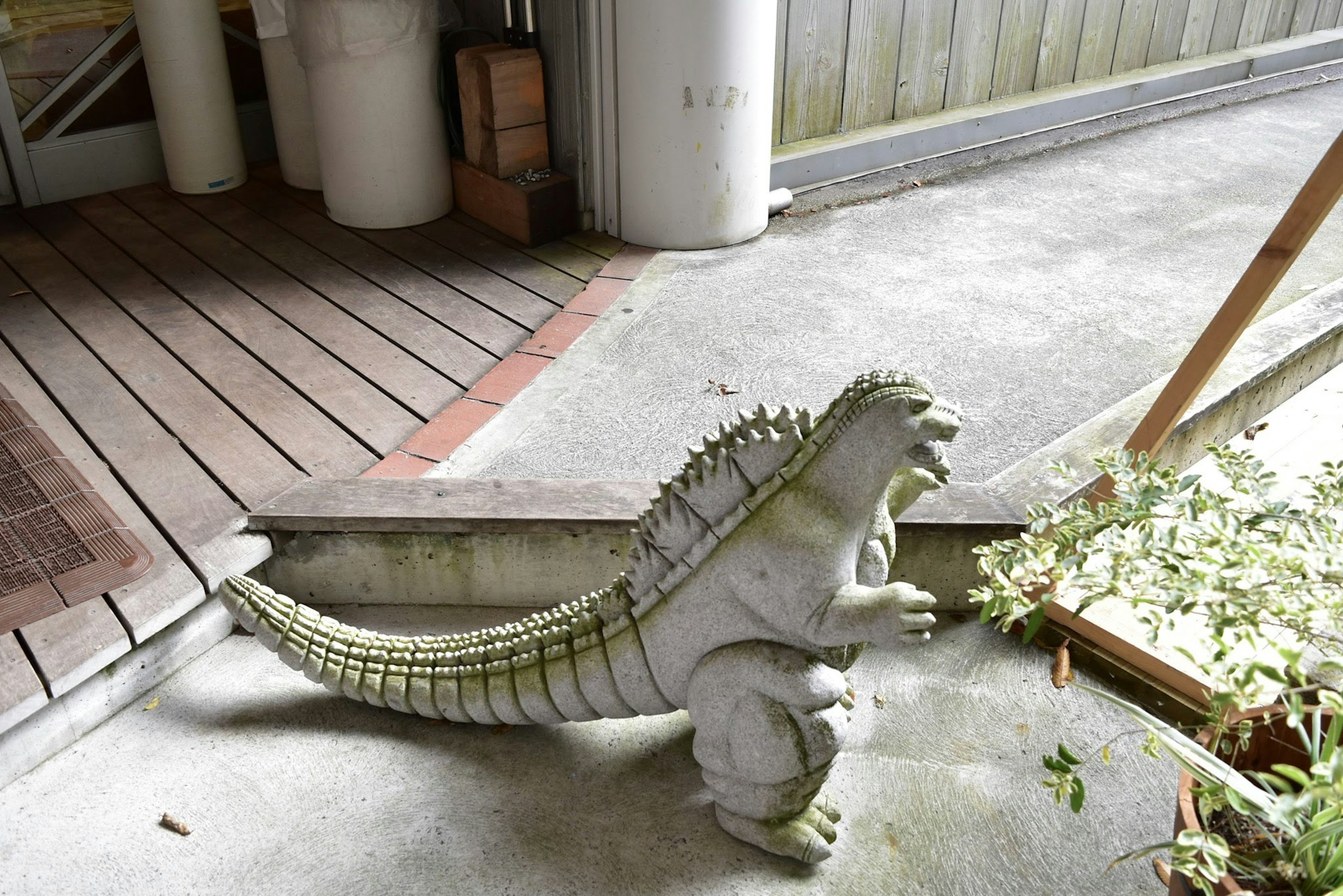 Patung dinosaurus beton yang ditempatkan dekat pintu masuk