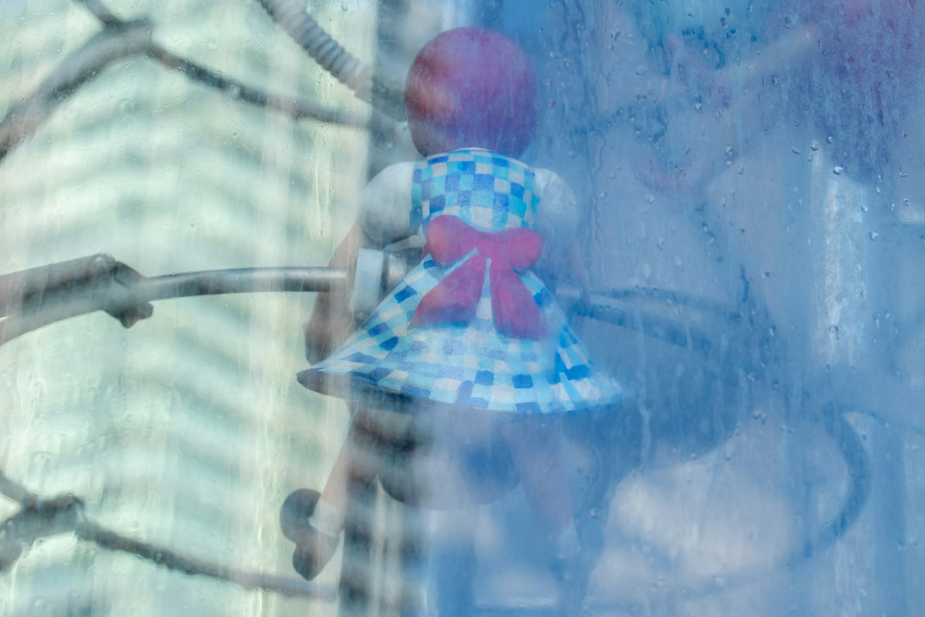 Una muñeca con un vestido a cuadros azules y un lazo rojo está trepando