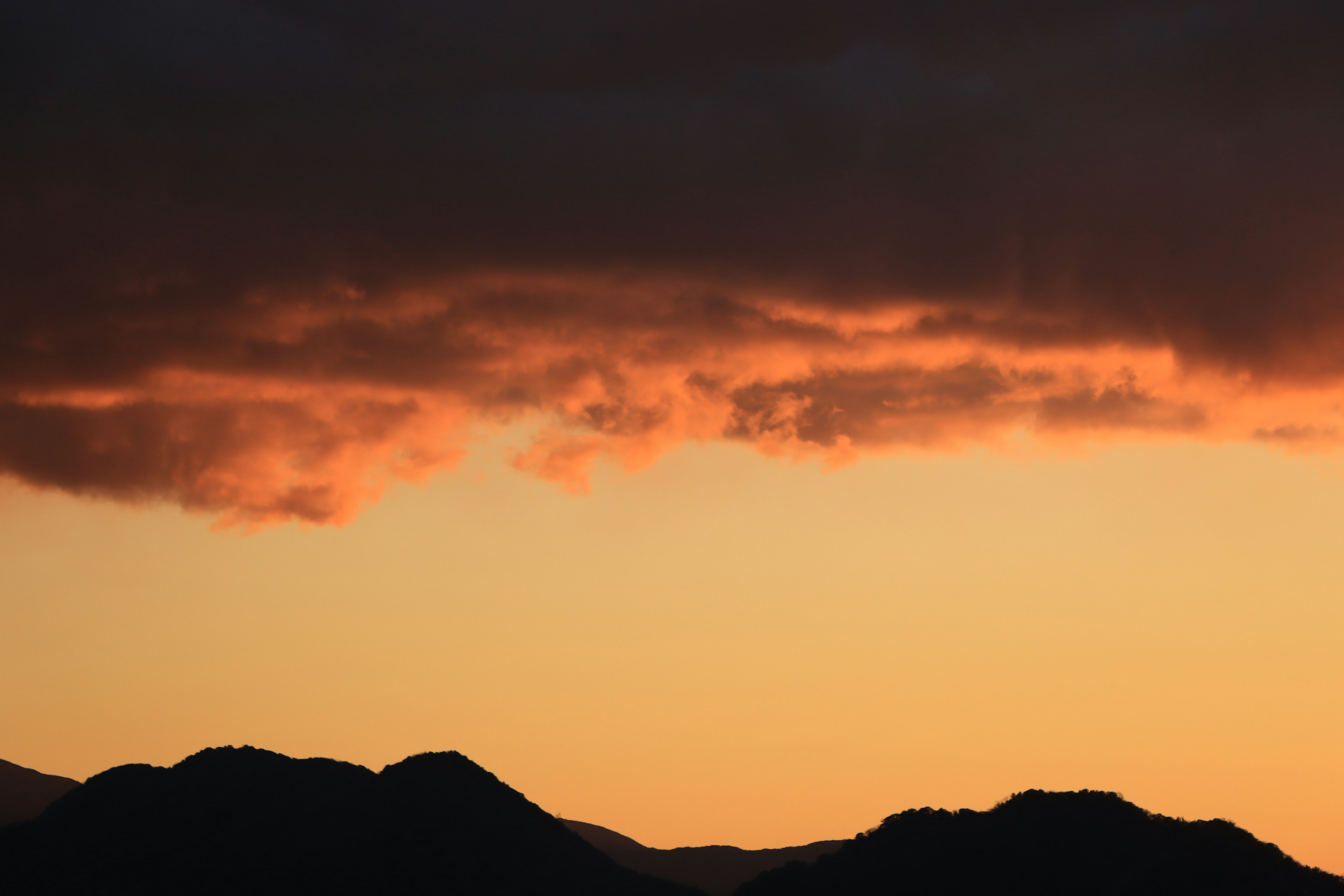 Orange sunset sky with mountain silhouettes