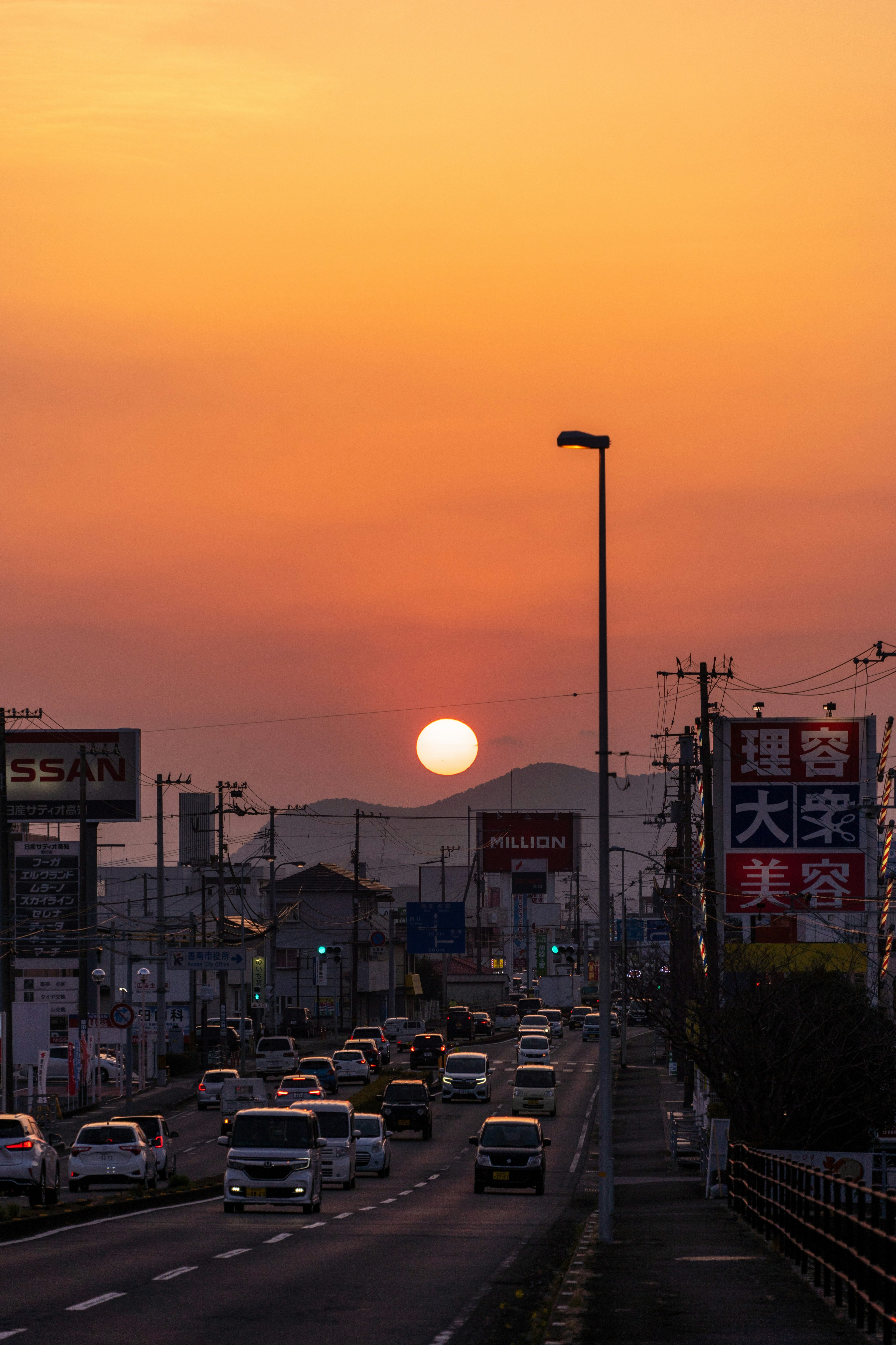 Coucher de soleil sur une route animée avec des montagnes en silhouette