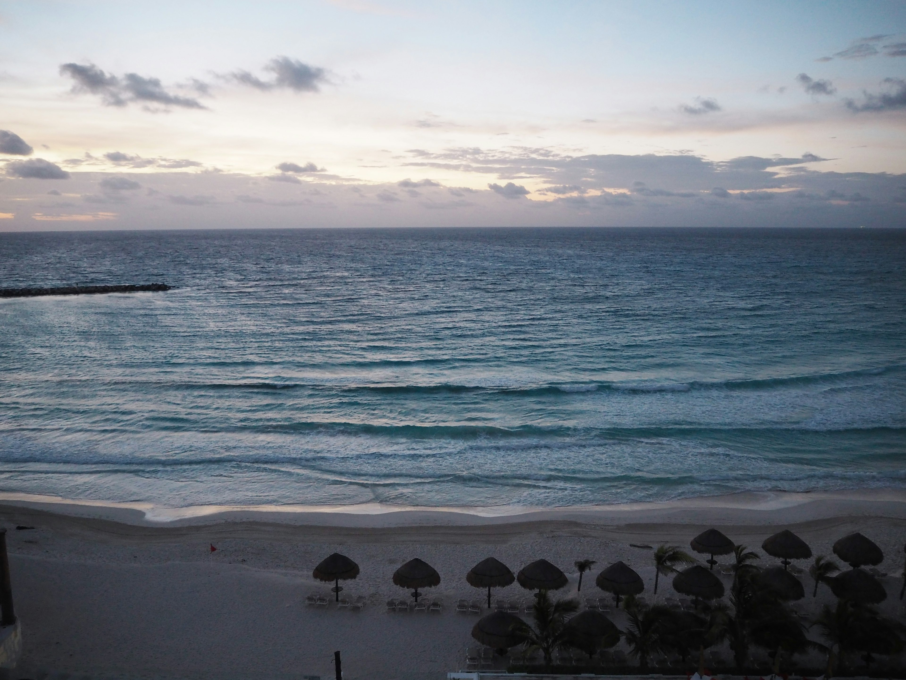 Caribbean Sea waves and beach scene at dusk with clouds