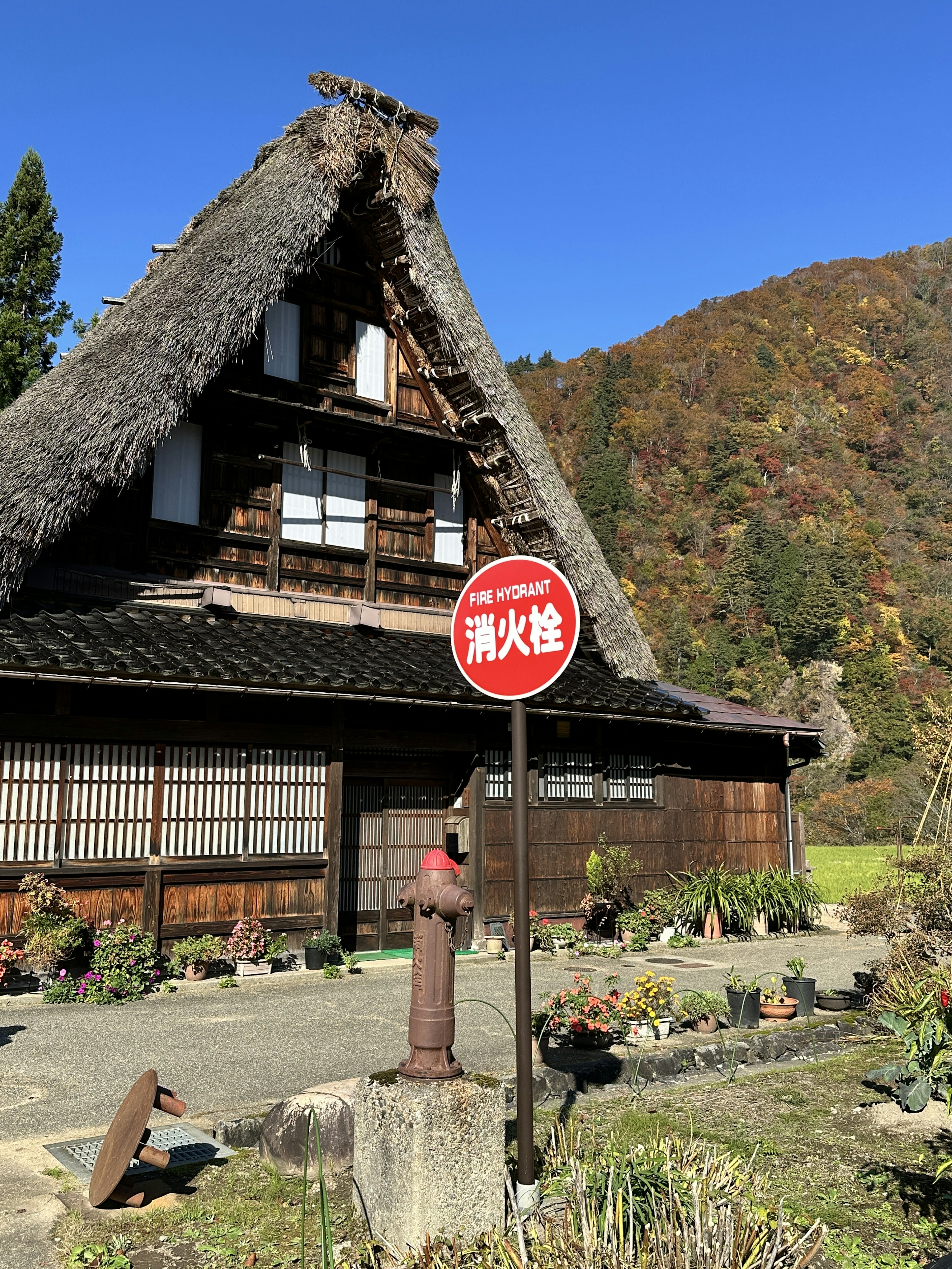 Maison traditionnelle à toit de chaume avec un panneau rouge au premier plan