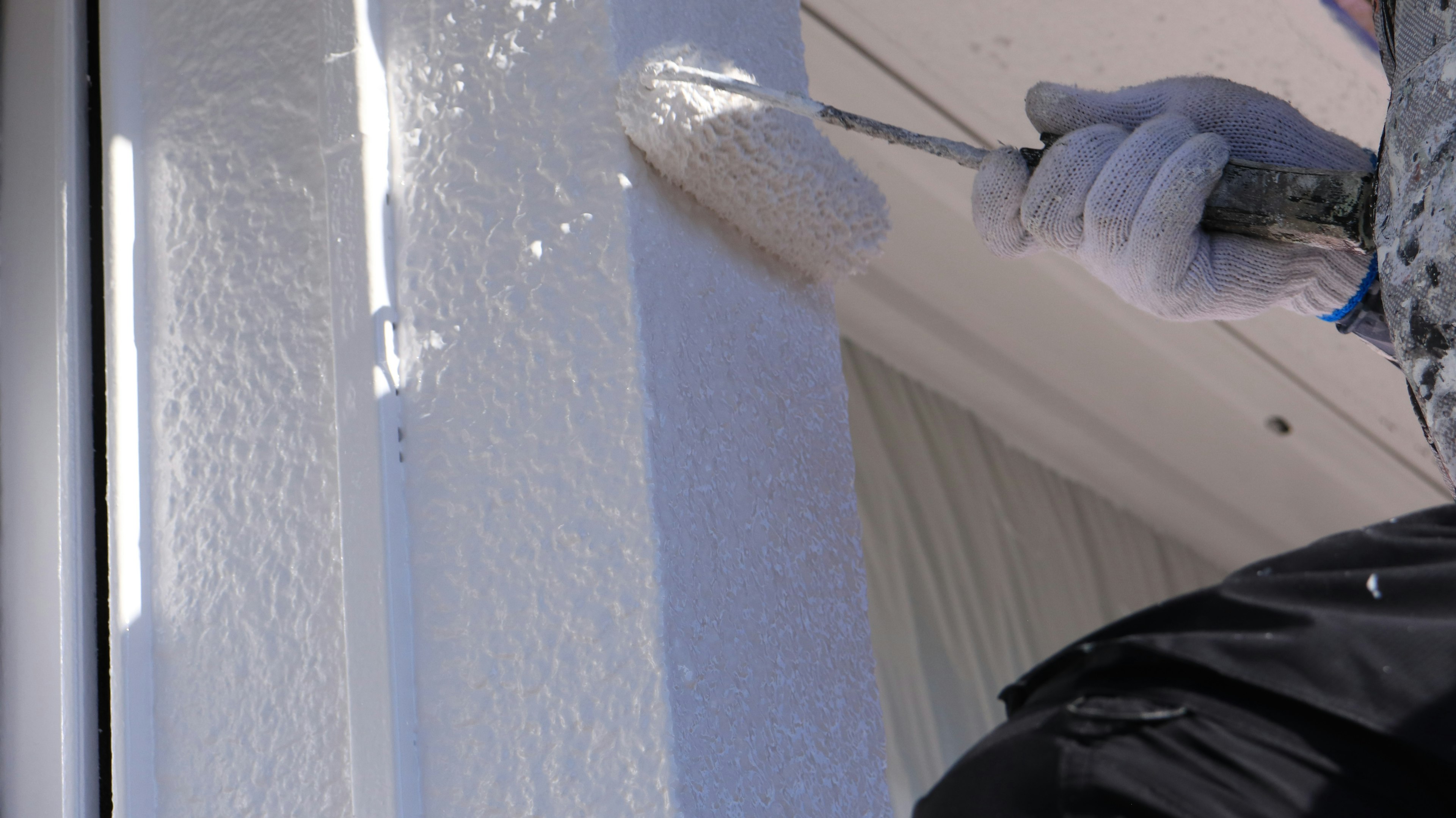 Persona che dipinge un muro bianco con un rullo