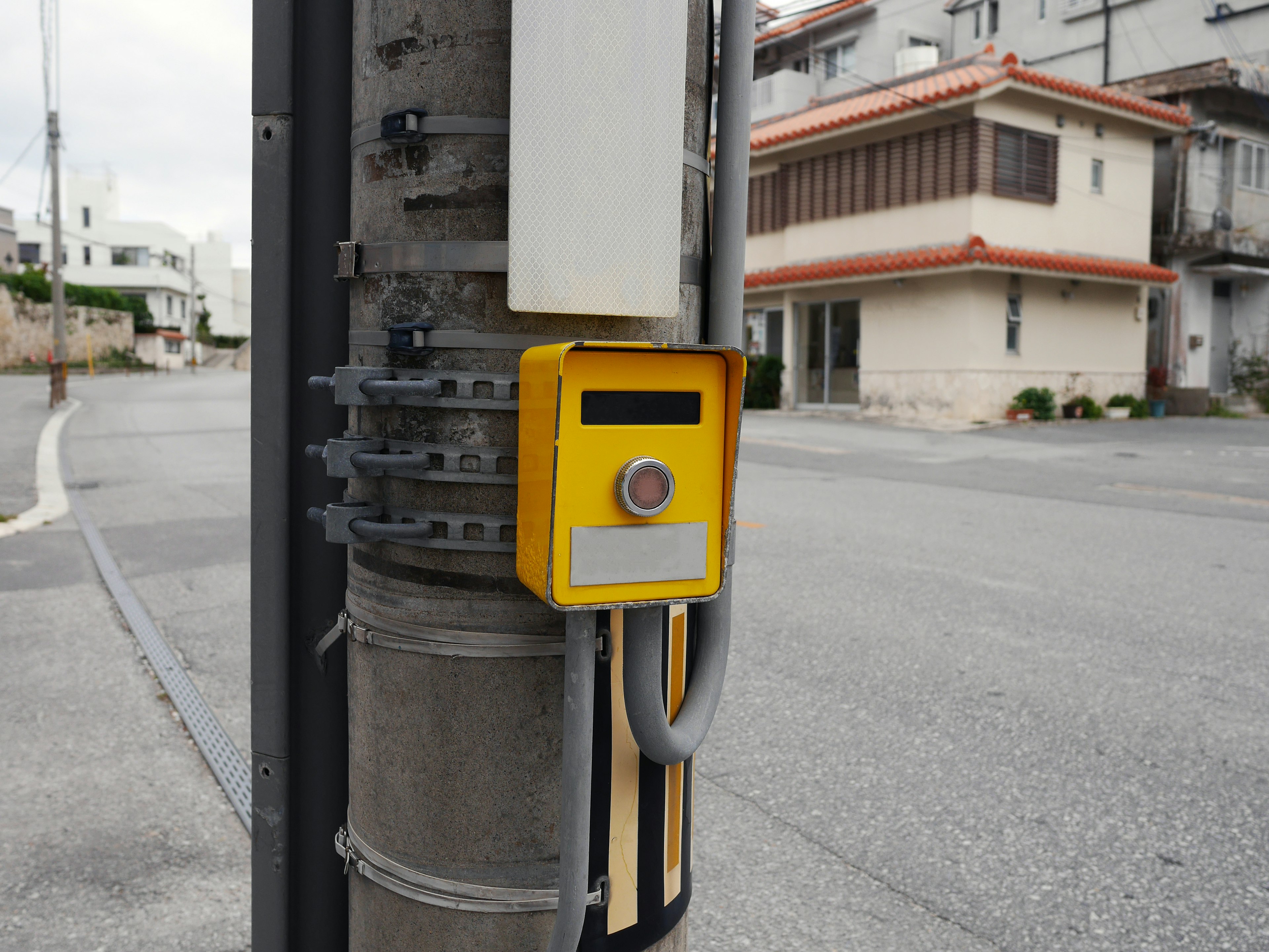 Un dispositivo amarillo con un botón montado en un poste de servicio