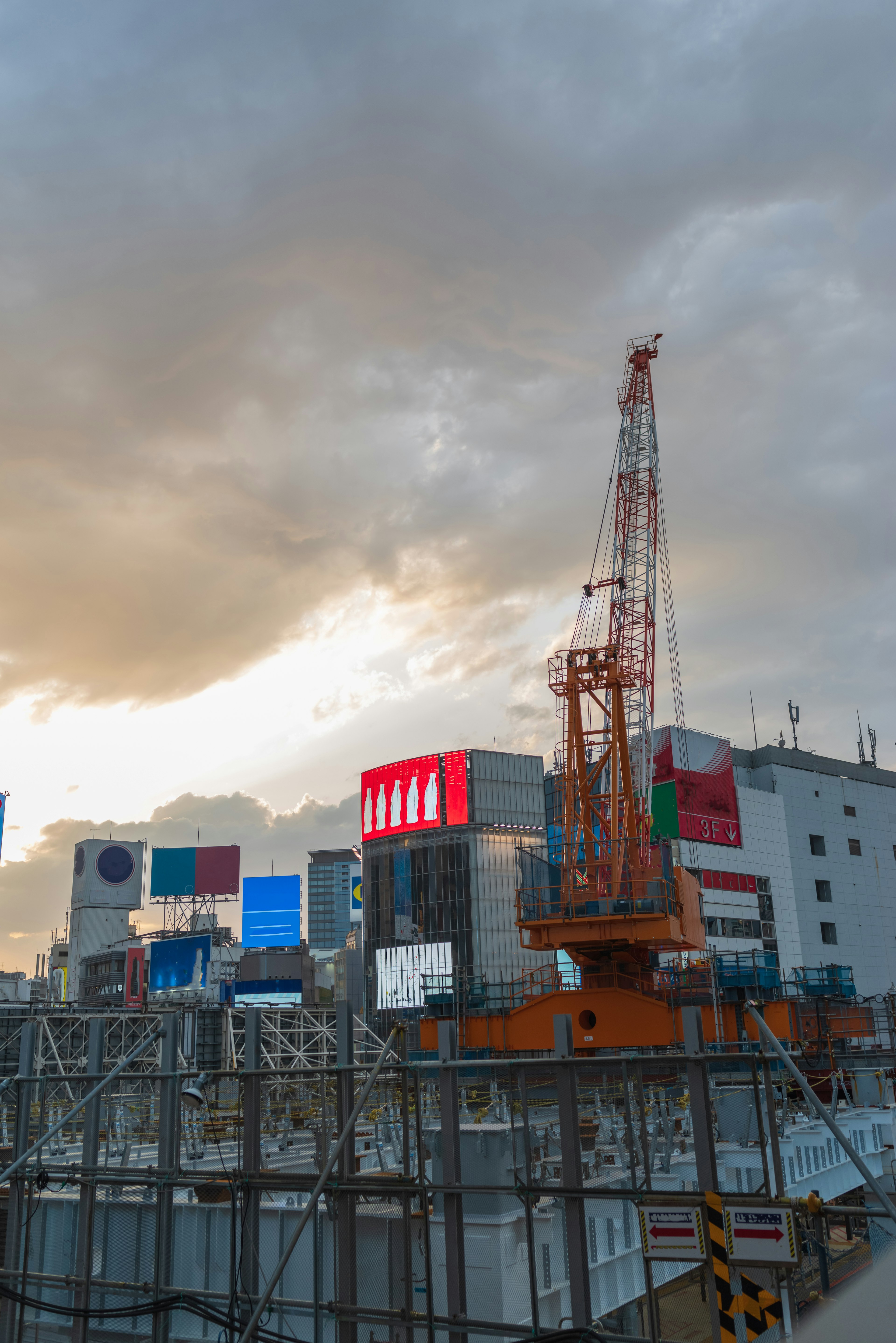 Situs konstruksi dengan crane dan papan bangunan di bawah langit senja