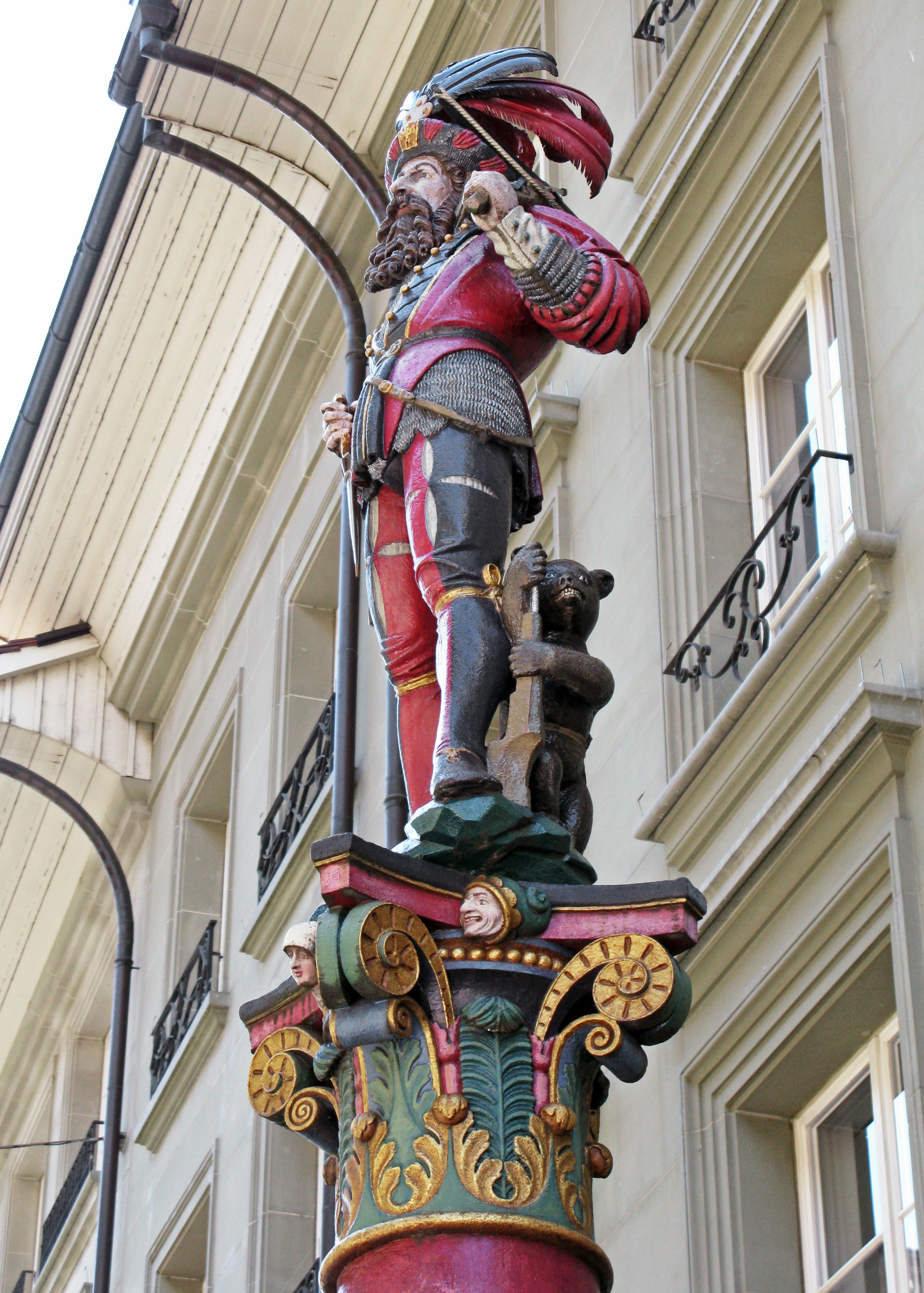 Una statua colorata di un guerriero e un orso su una colonna decorativa