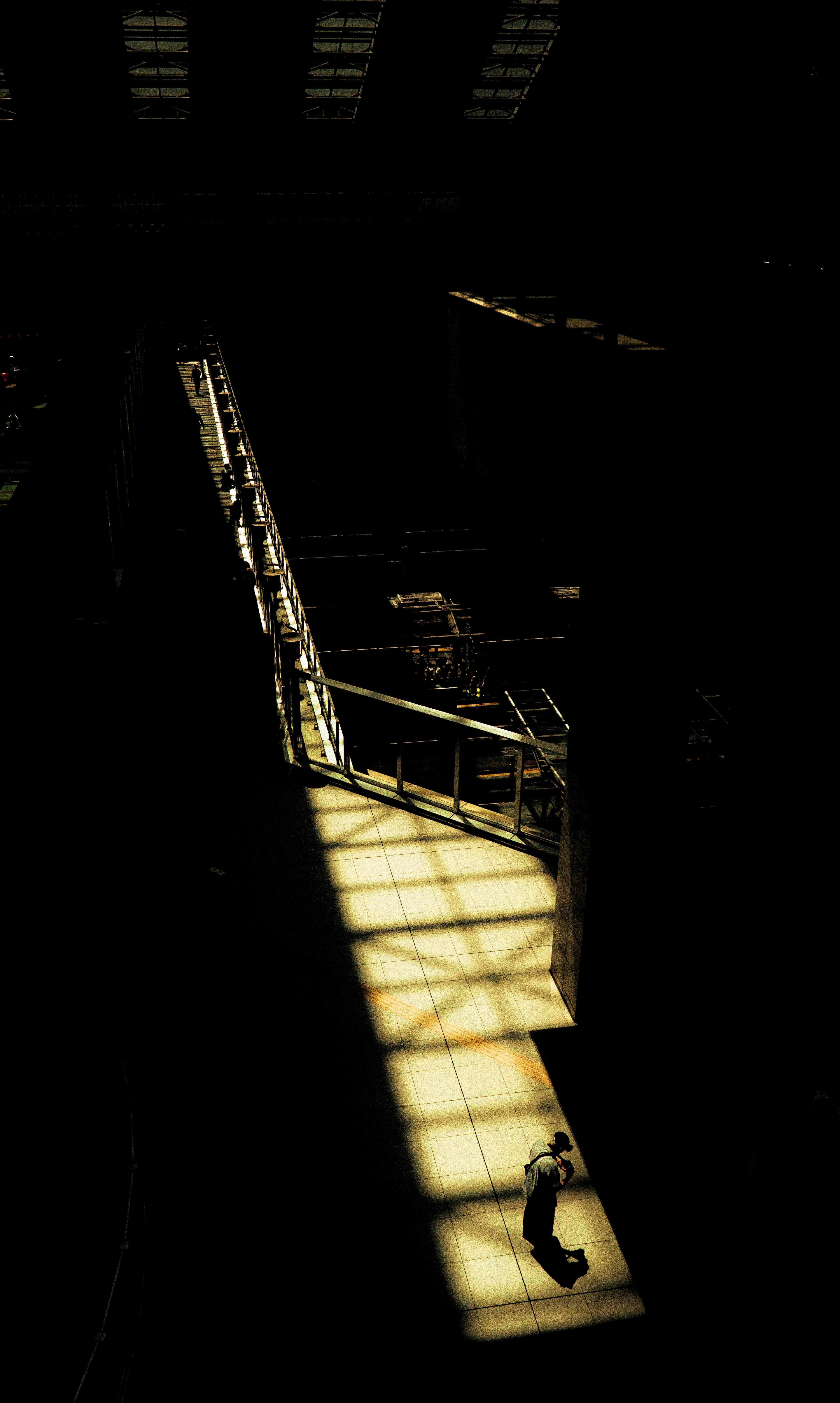 Una persona caminando en un espacio industrial iluminado por luz brillante y sombras