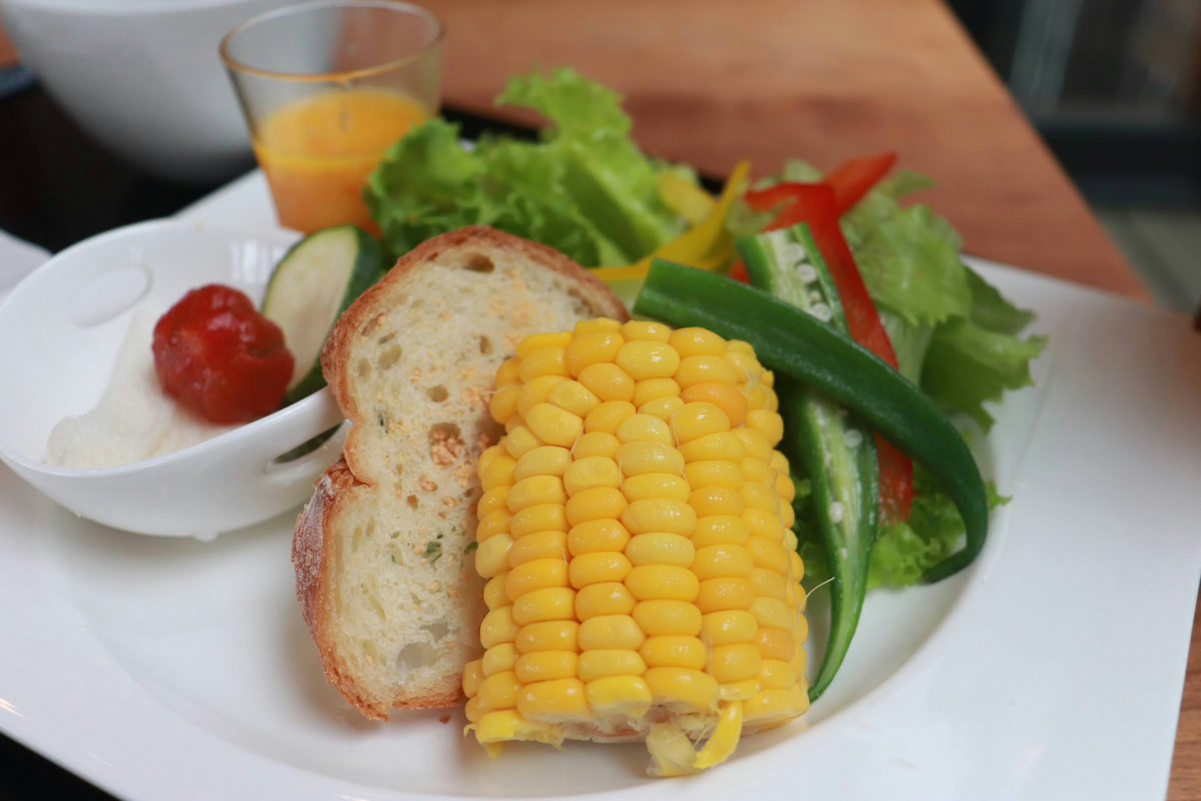 Piring salad segar dengan jagung roti panggang dan tomat ceri dengan mangkuk kecil saus