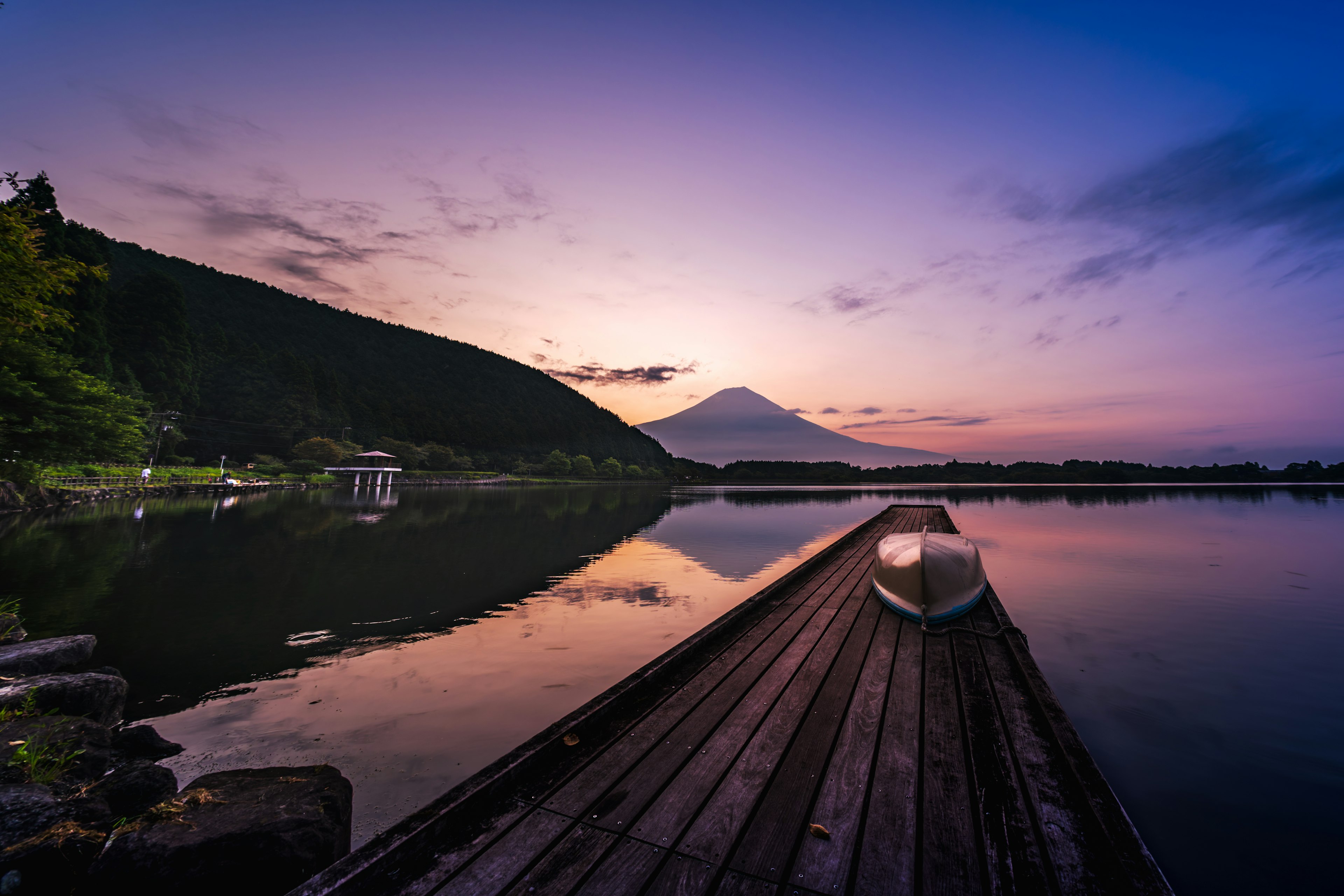 Vista del tramonto sul Monte Fuji sopra un lago con una piccola barca su un molo