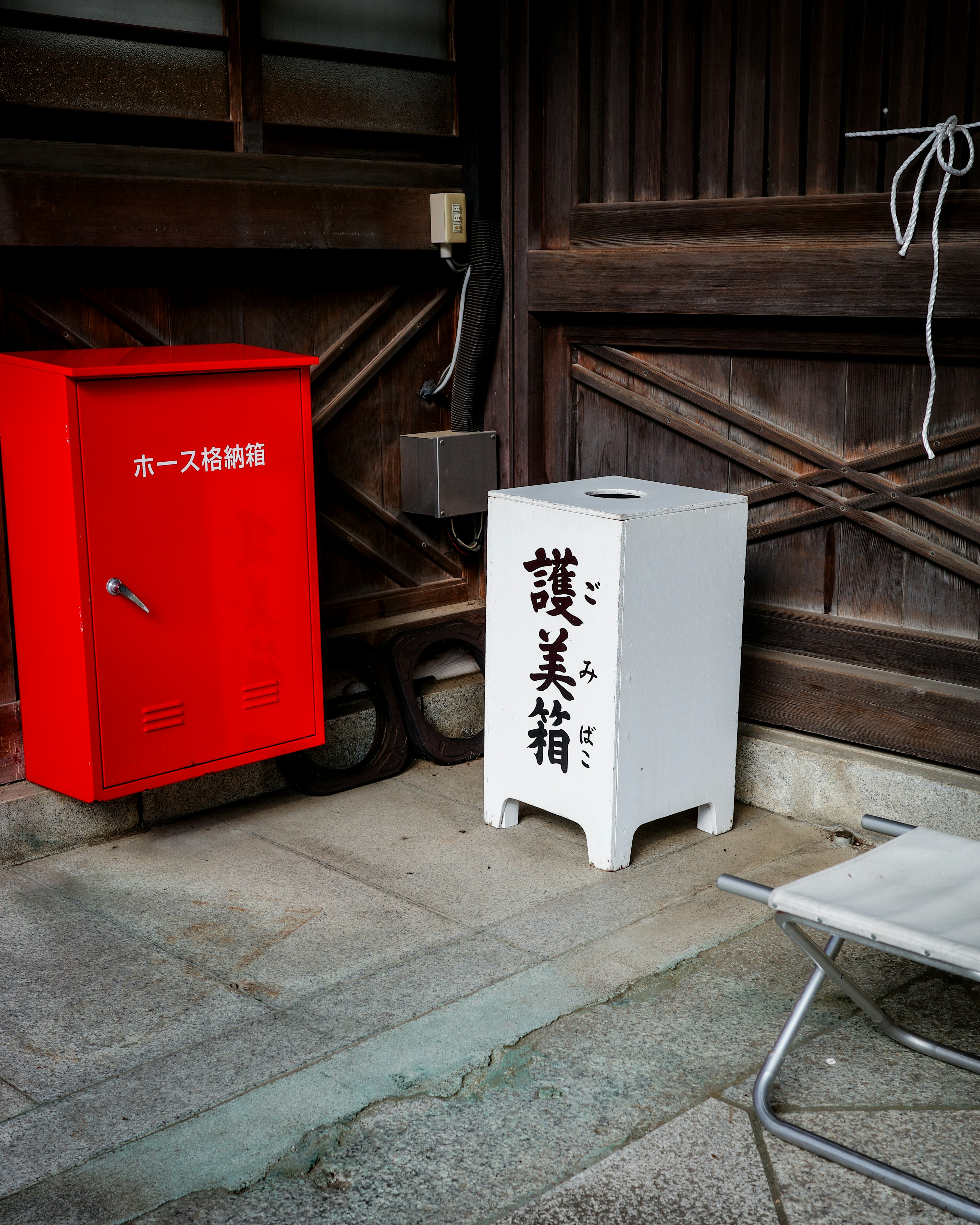 A white postal box and a red postal box side by side in a Japanese street corner