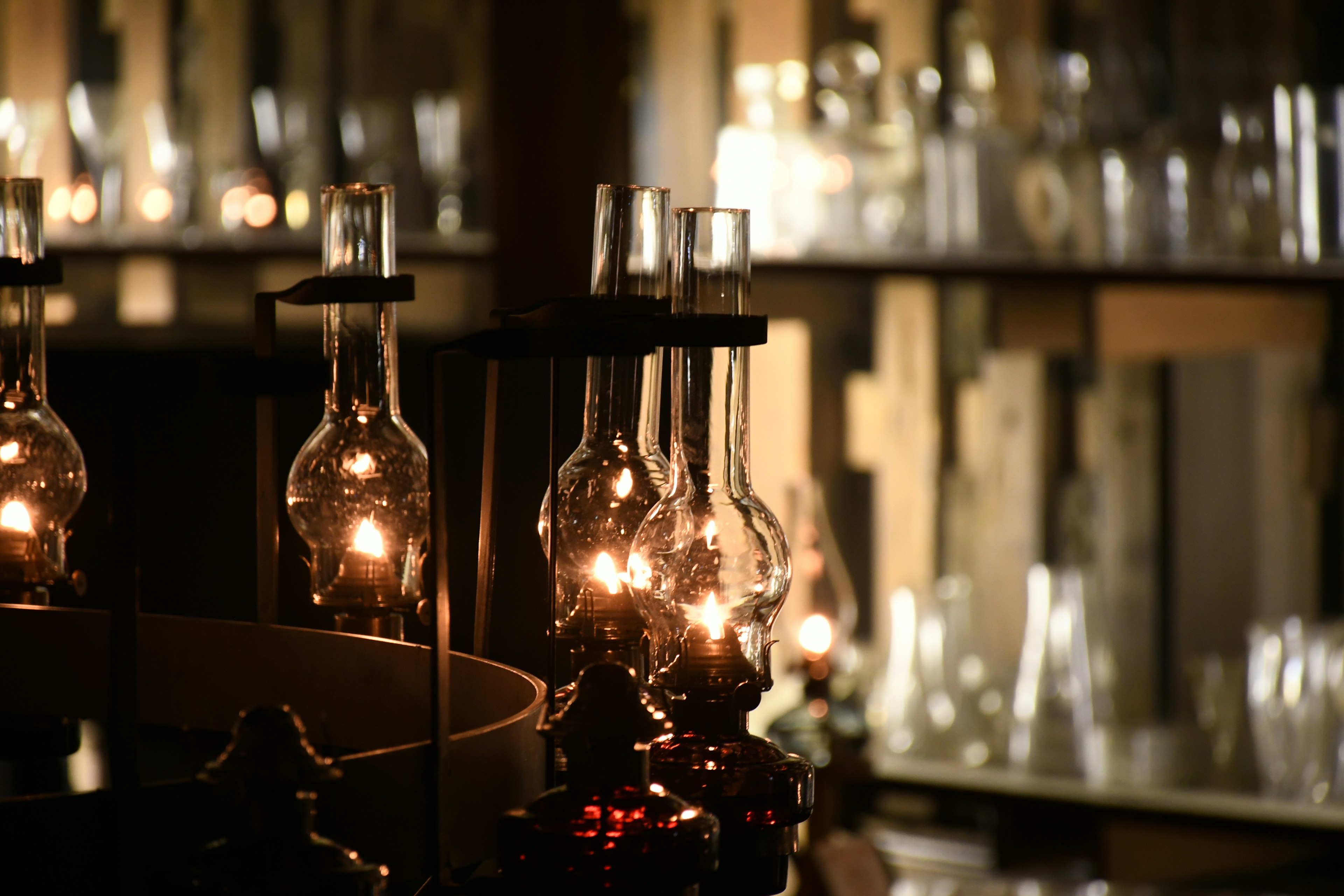 Image of lit vintage lamps with glass bottles in the background