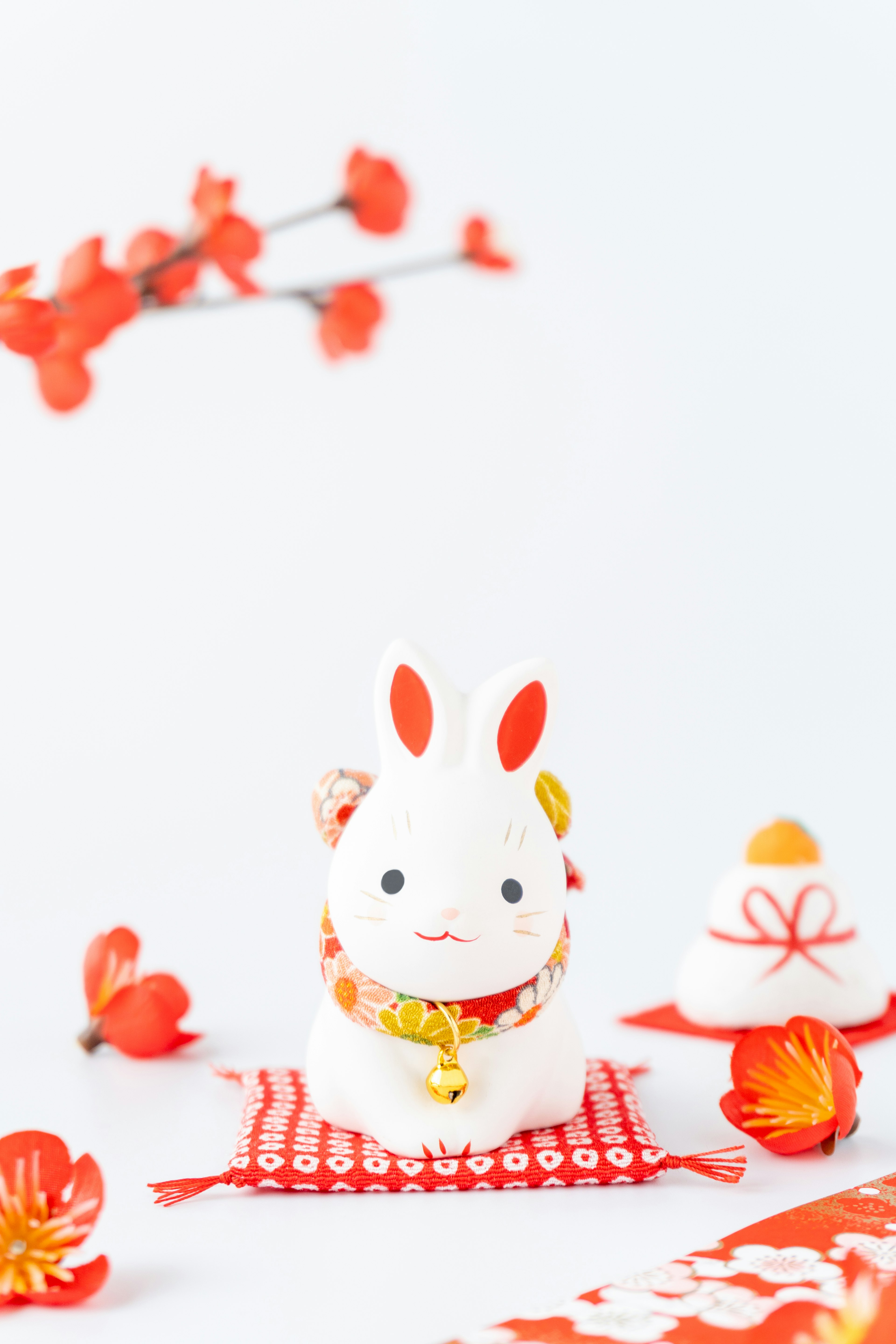 Figurine décorative de lapin blanc avec des accents rouges entourée de fleurs en fleurs