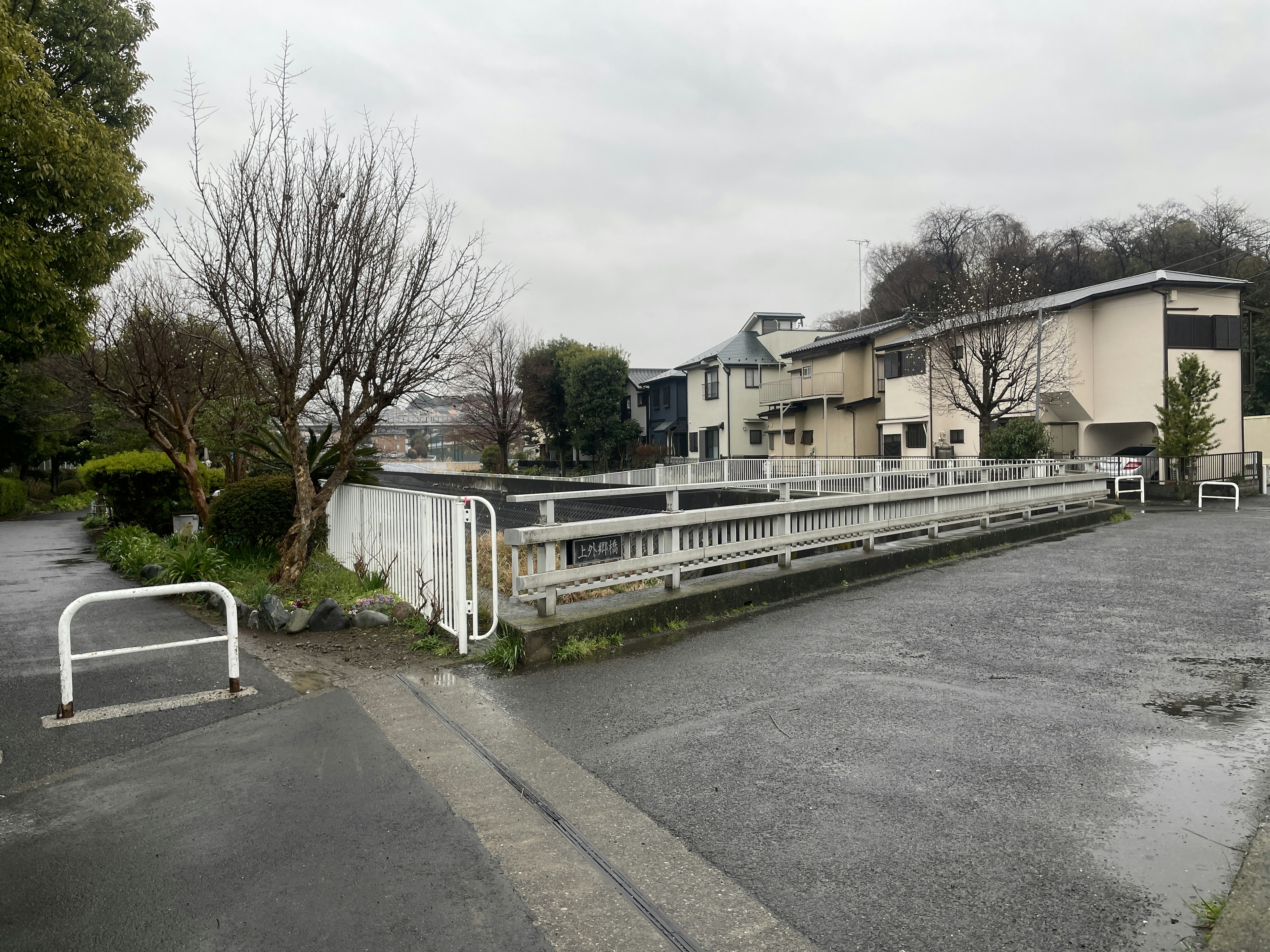 A quiet street scene featuring residential buildings and a walkway on a rainy day