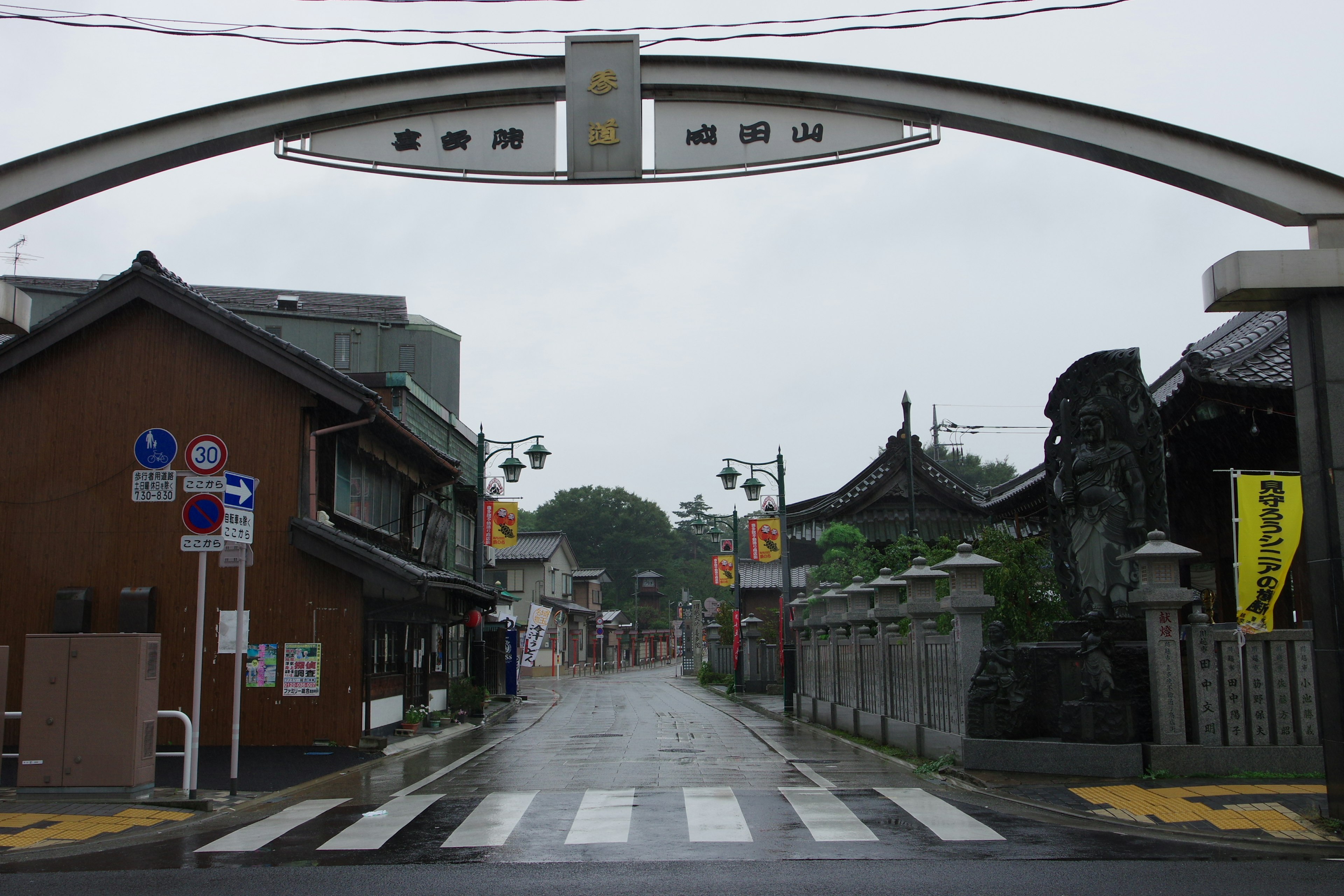 Entrée en arc par un jour de pluie avec des bâtiments traditionnels le long d'une rue calme