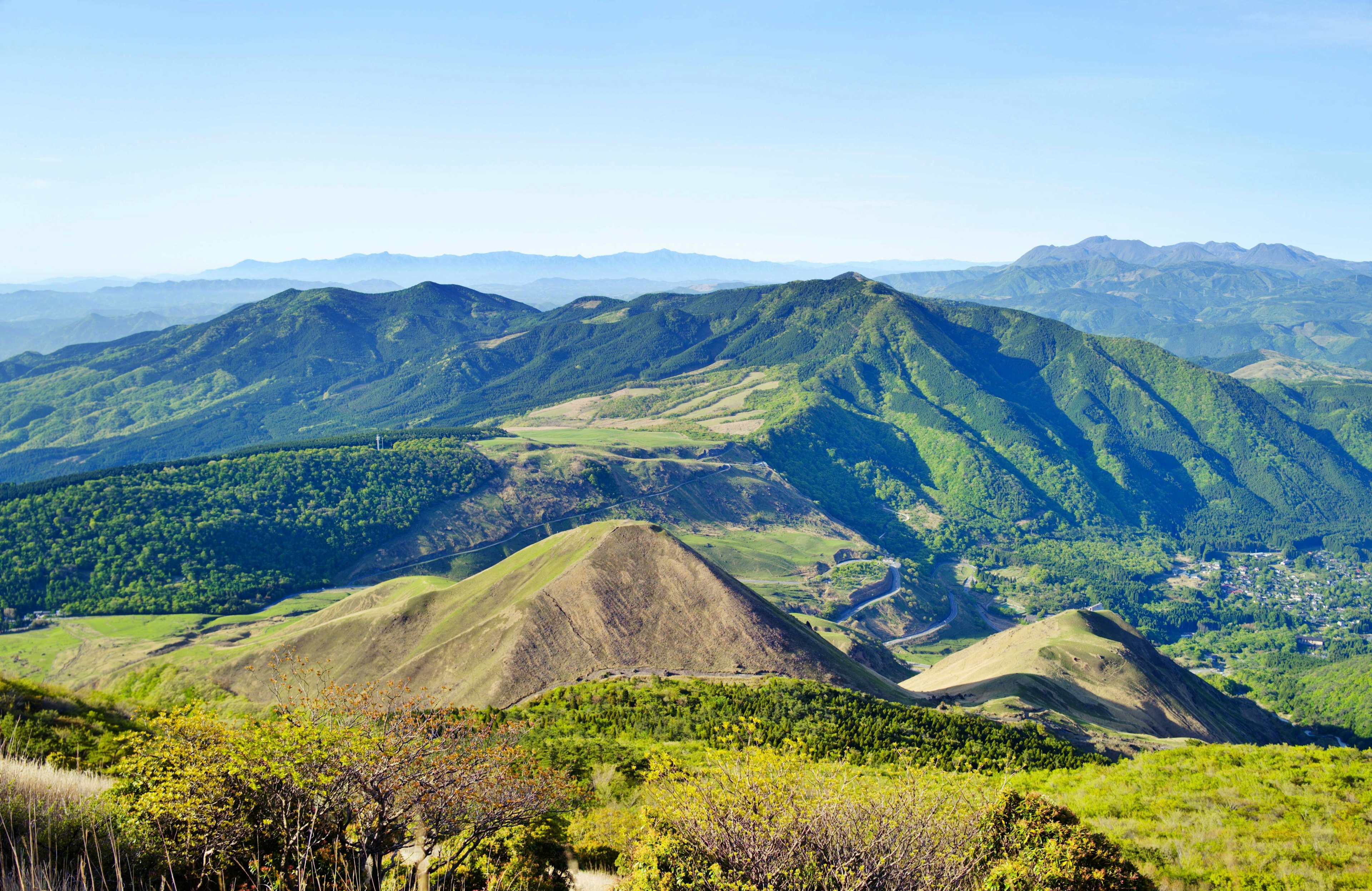 Vista escénica de montañas y colinas verdes bajo un cielo azul claro