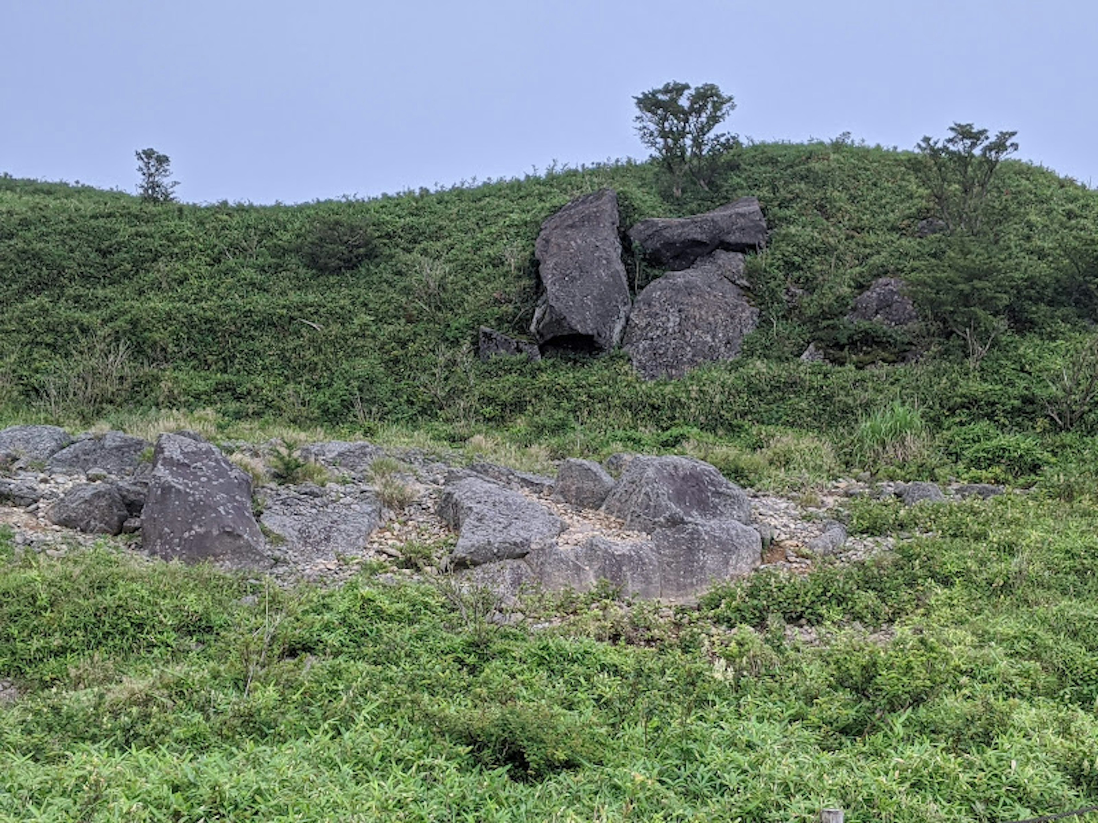 Bukit berbatu yang ditutupi vegetasi hijau dan bebatuan yang tersebar