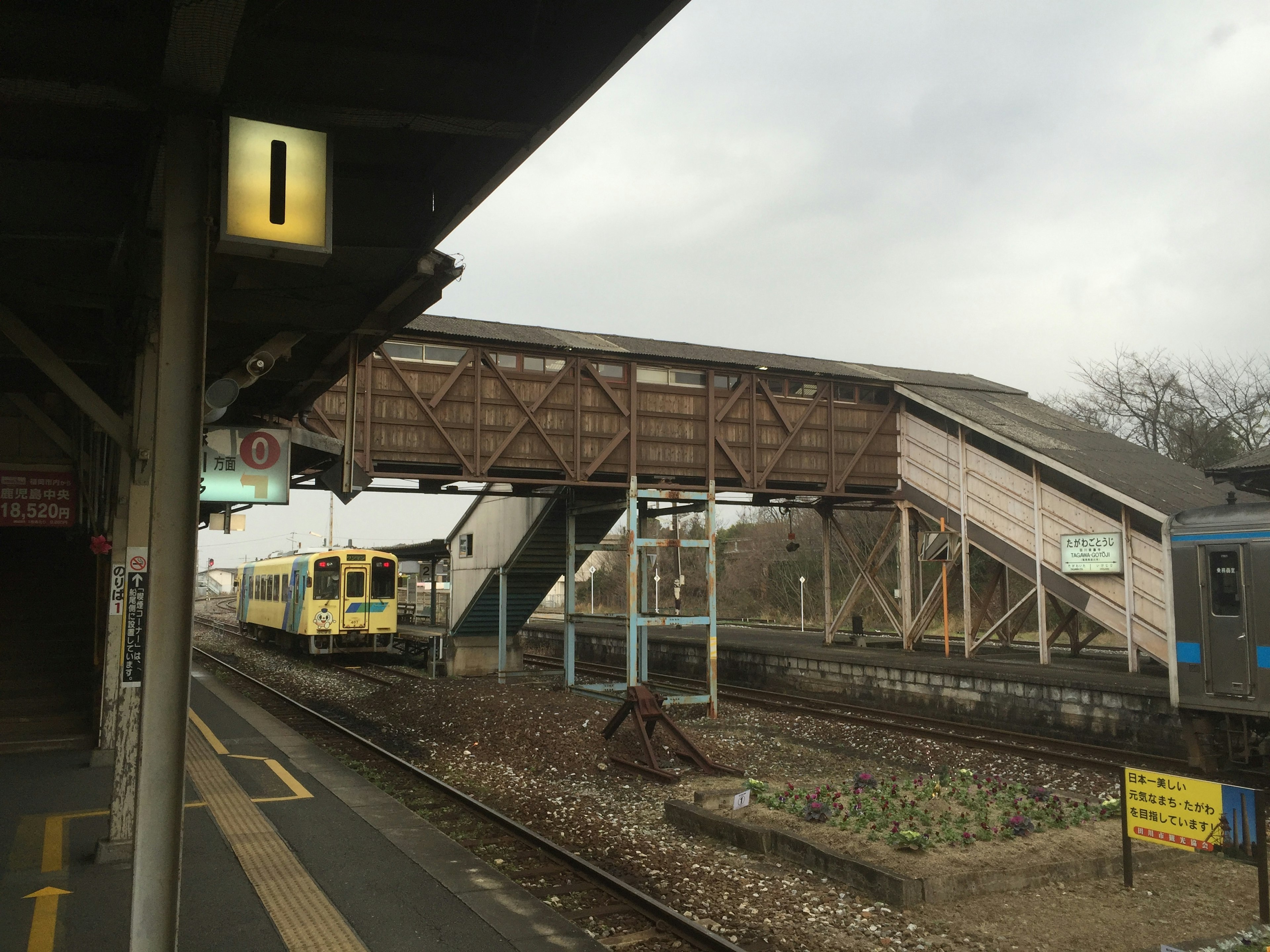 Tren y pasarela de madera vistos desde la plataforma de la estación