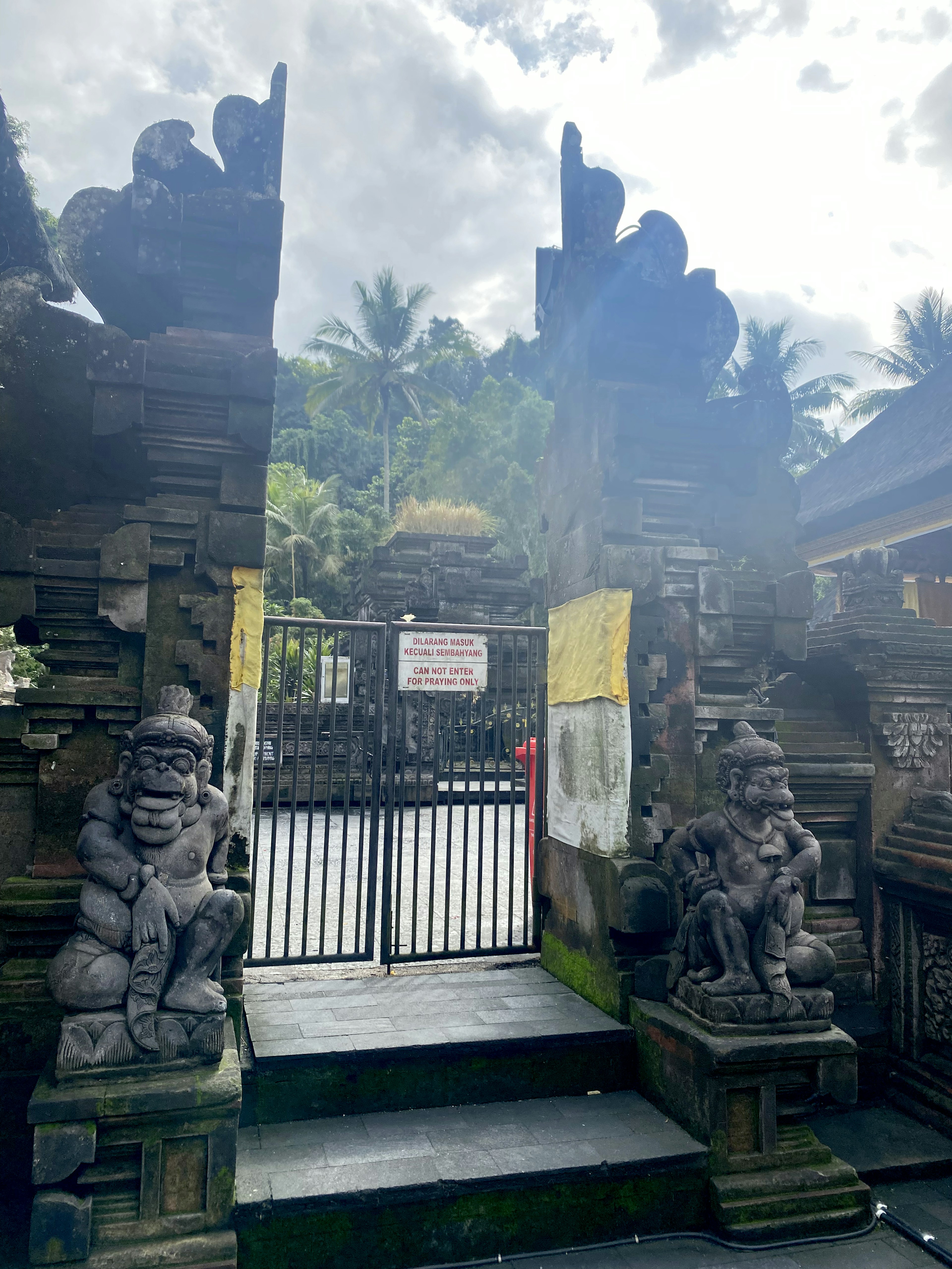 Balinese temple gate with stone carvings green plants blue sky