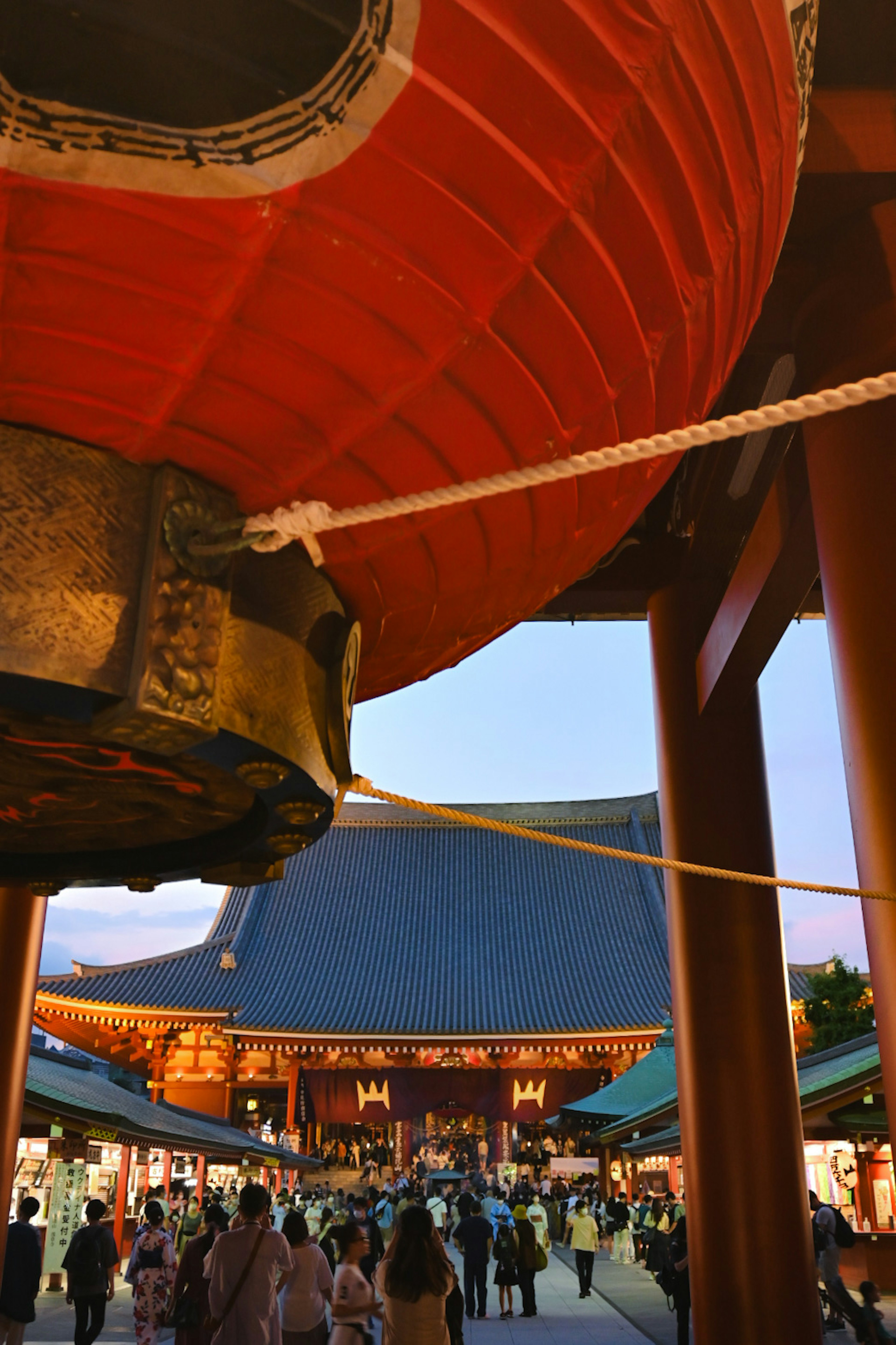 Vue du temple Senso-ji encadré par une grande lanterne rouge avec de nombreuses personnes rassemblées