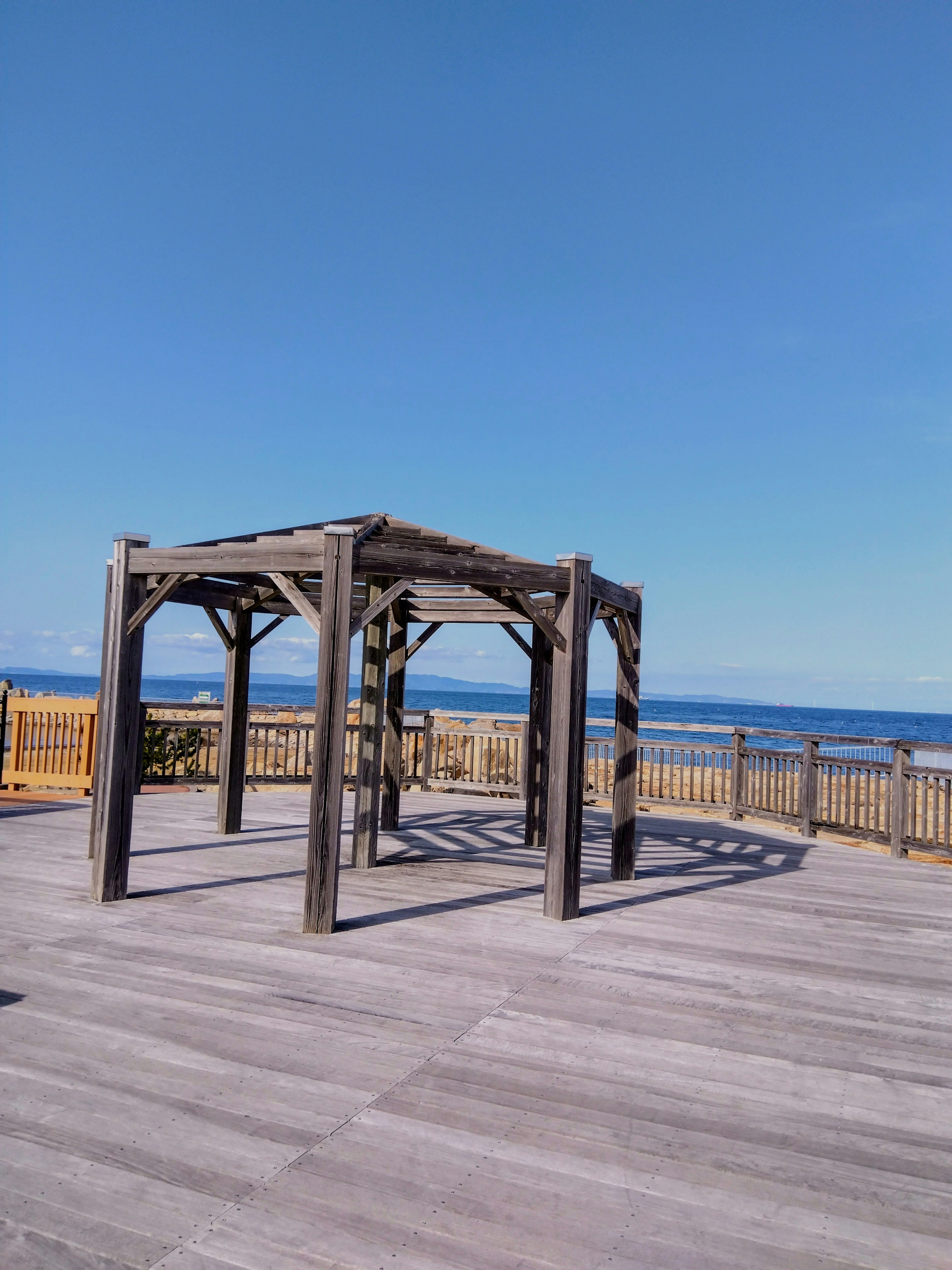 Pergola kayu menghadap lautan dan langit biru cerah