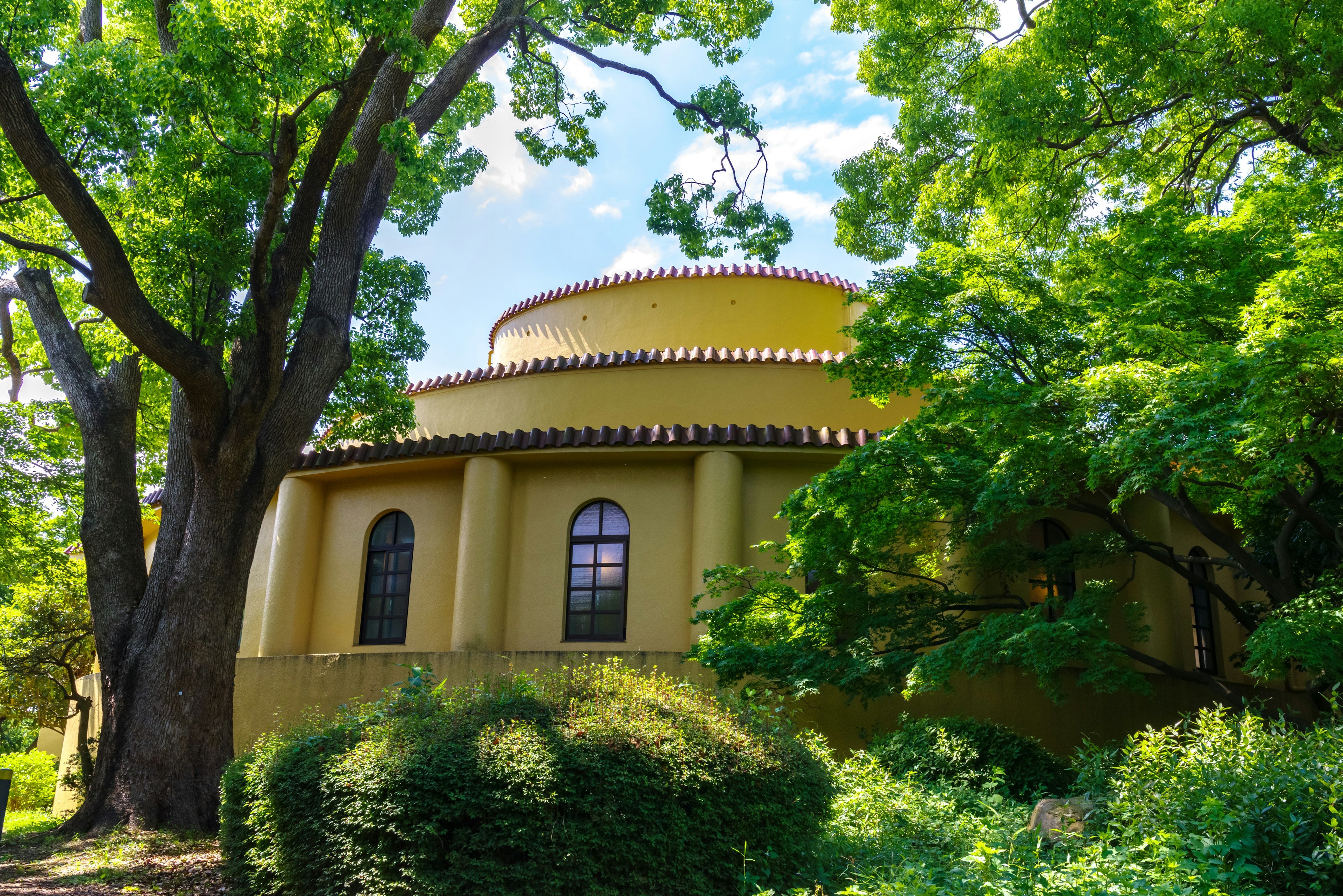 Yellow building surrounded by green trees and blue sky