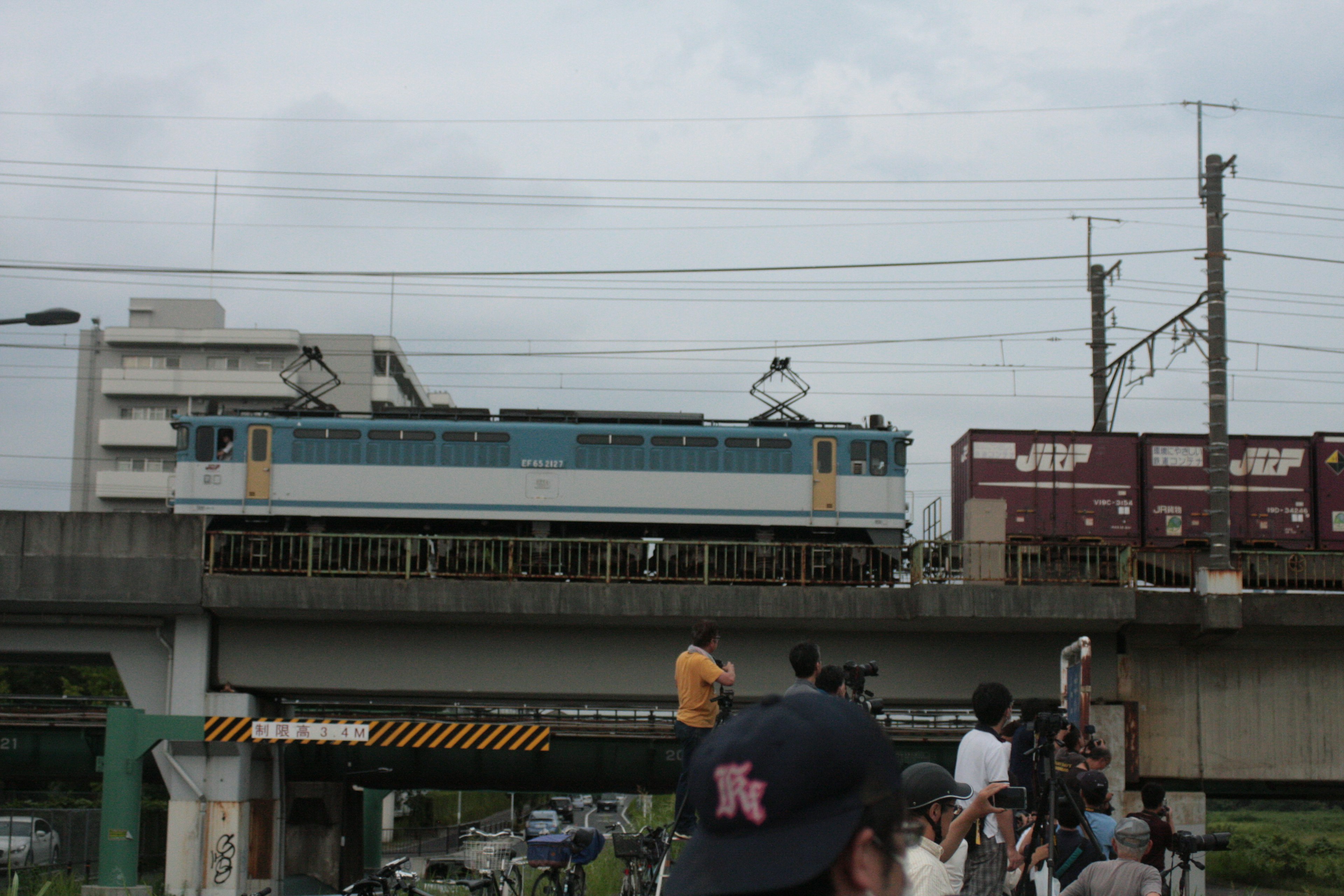 Lokomotif biru menarik kereta barang di atas jembatan